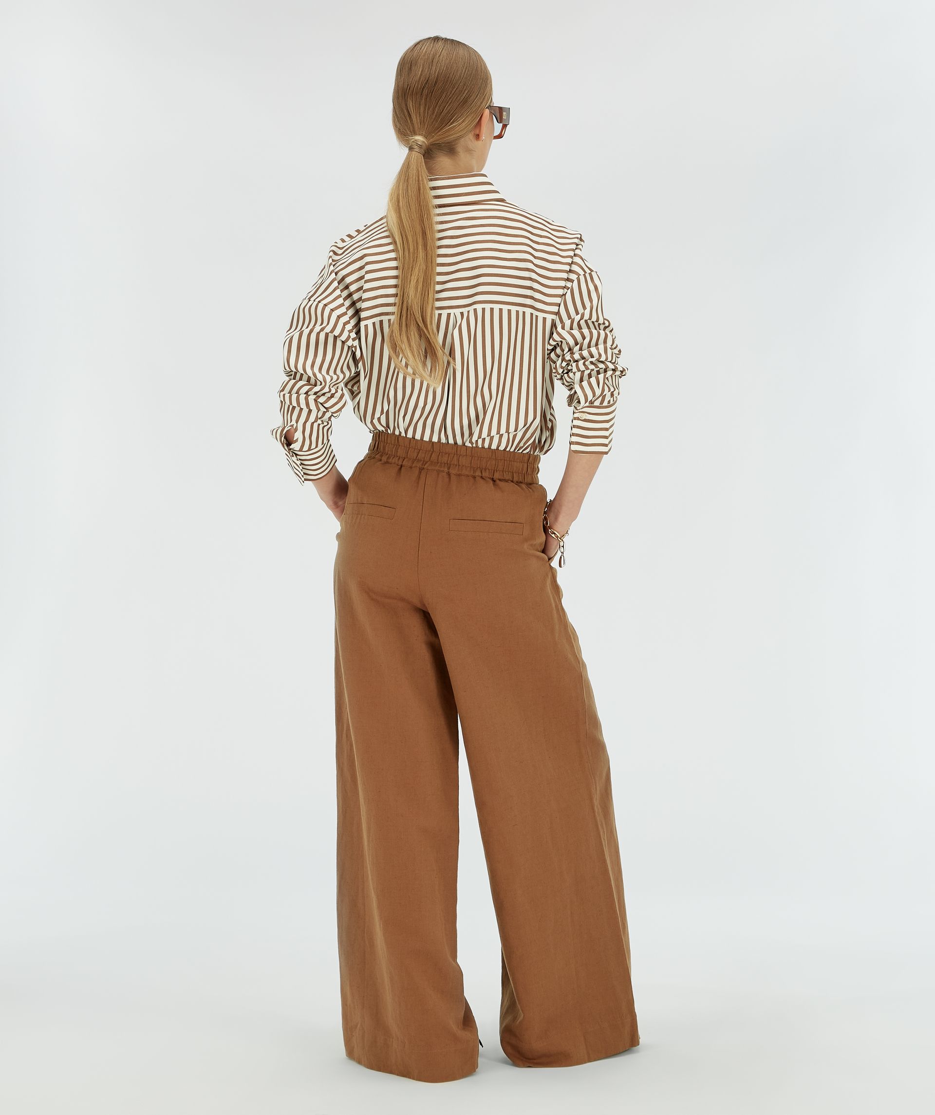 Achteraanzicht van een model in een donkerbruine wide leg broek.