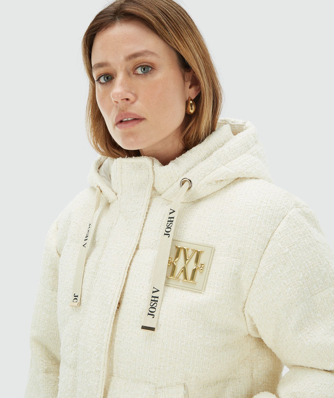 Model draagt een Creme White gewatteerde jas met capuchon en gouden JOSH V monogram logo op de borst - Josh V