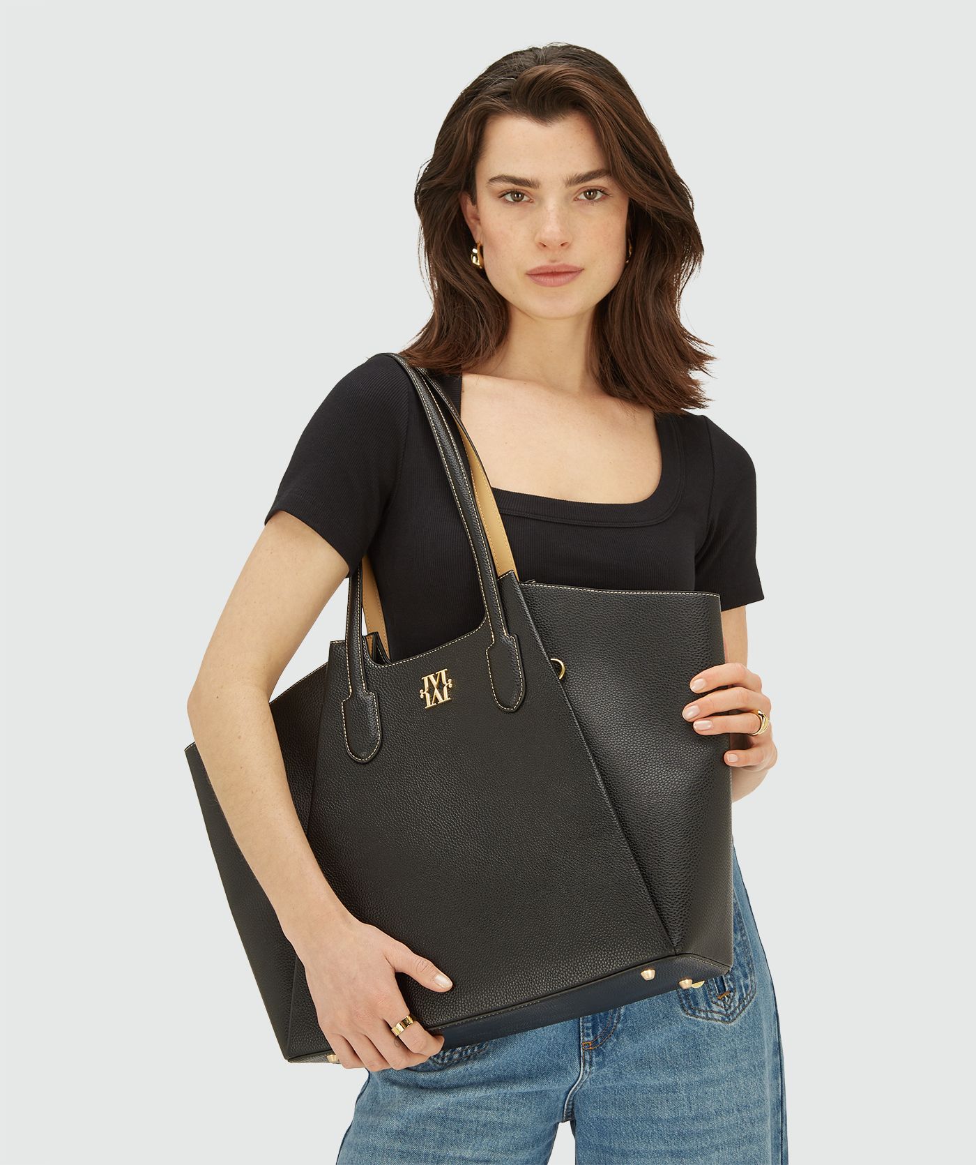 Model draagt zwarte shopper tas met dubbele hengsels en goudkleurig JOSH V logo