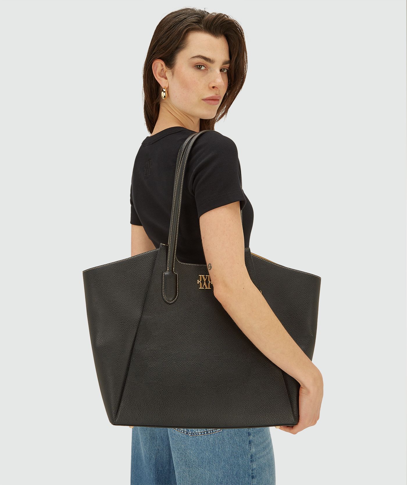 Model draagt zwarte shopper tas met dubbele hengsels en goudkleurig JOSH V logo
