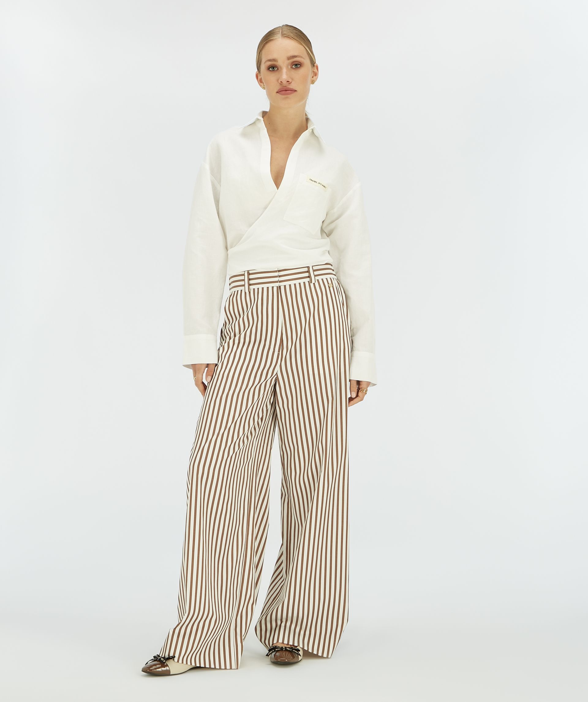Model draagt een witte cropped blouse met striksluiting.