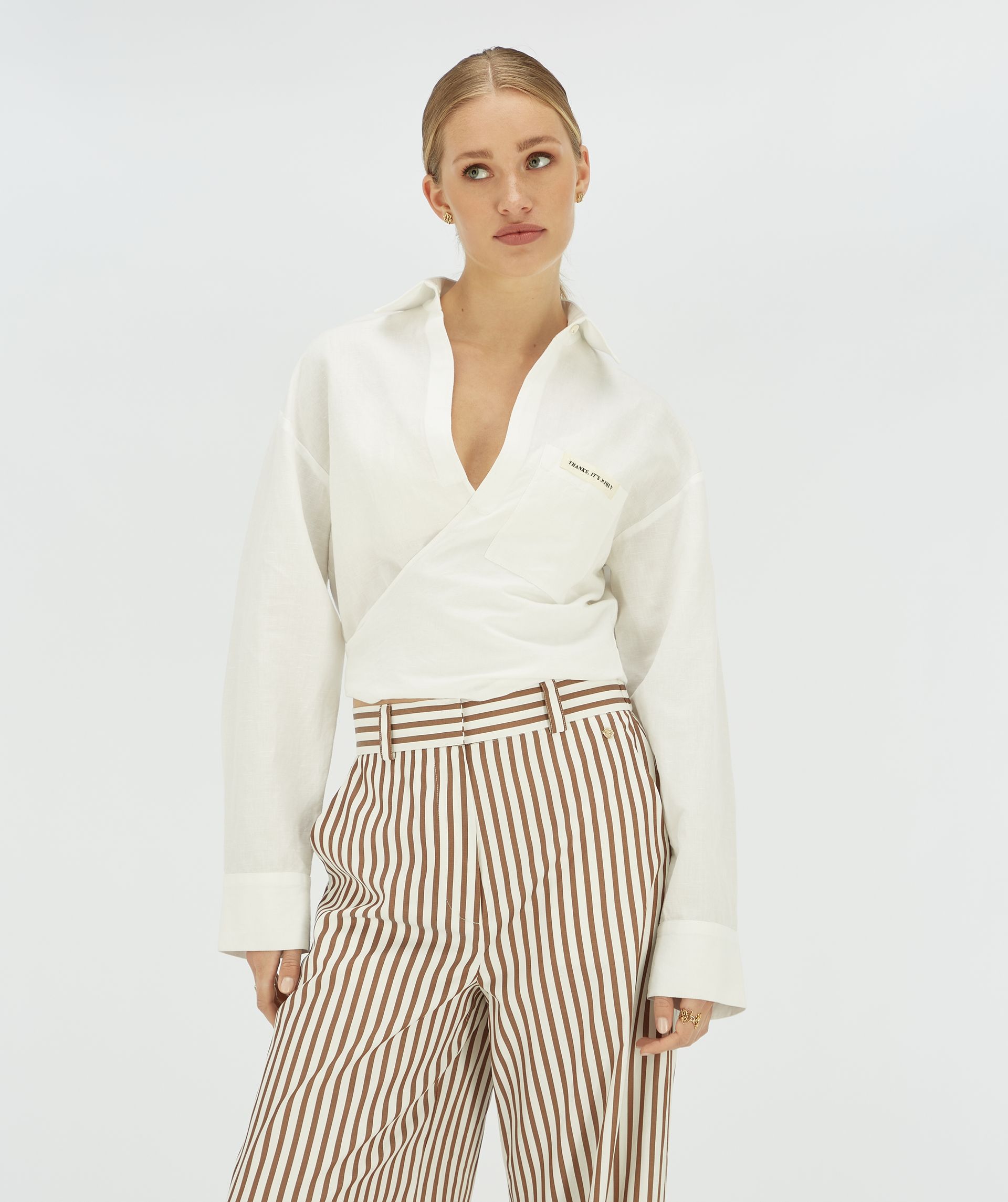 Model draagt een witte cropped blouse met striksluiting.