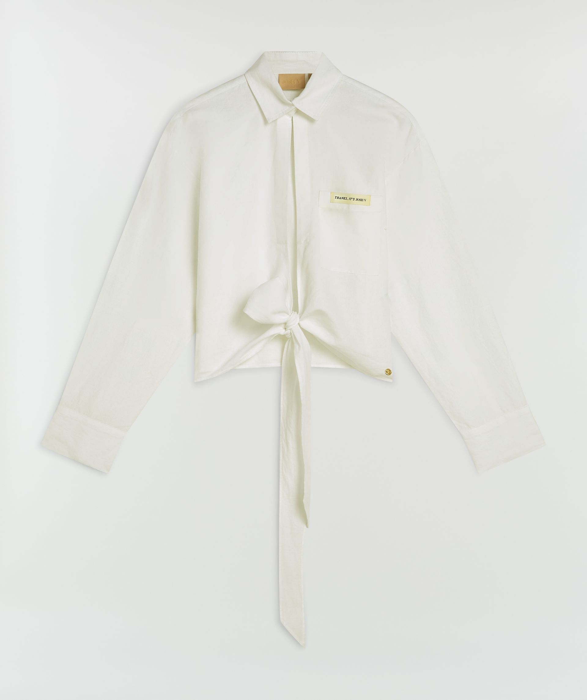 Witte cropped blouse met striksluiting zonder model, weergegeven op een lichtgrijze achtergrond 