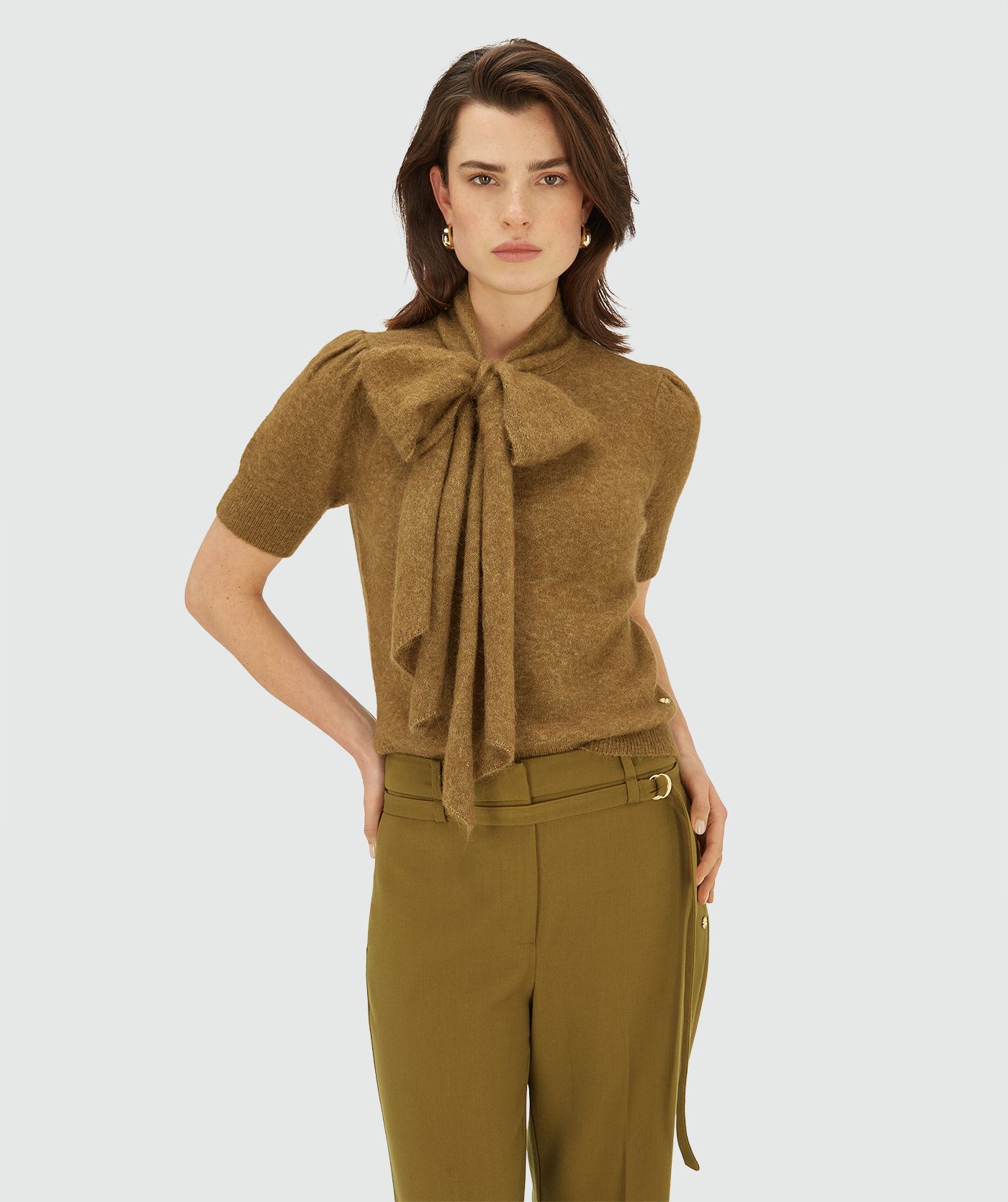 Model draagt een Olive Green Melange knit top met korte mouwen en strikdetail bij de hals
