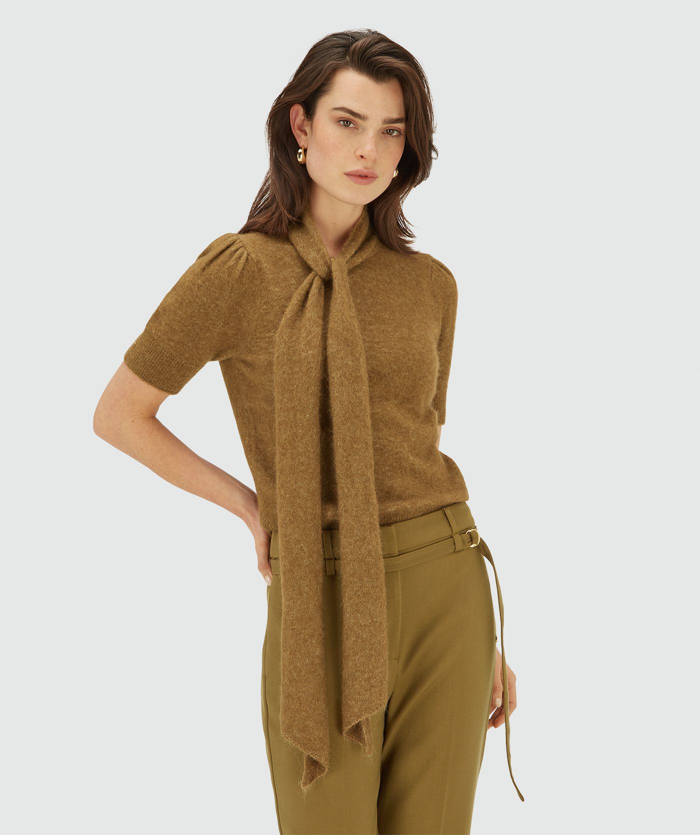 Model draagt een Olive Green Melange knit top met korte mouwen en strikdetail bij de hals