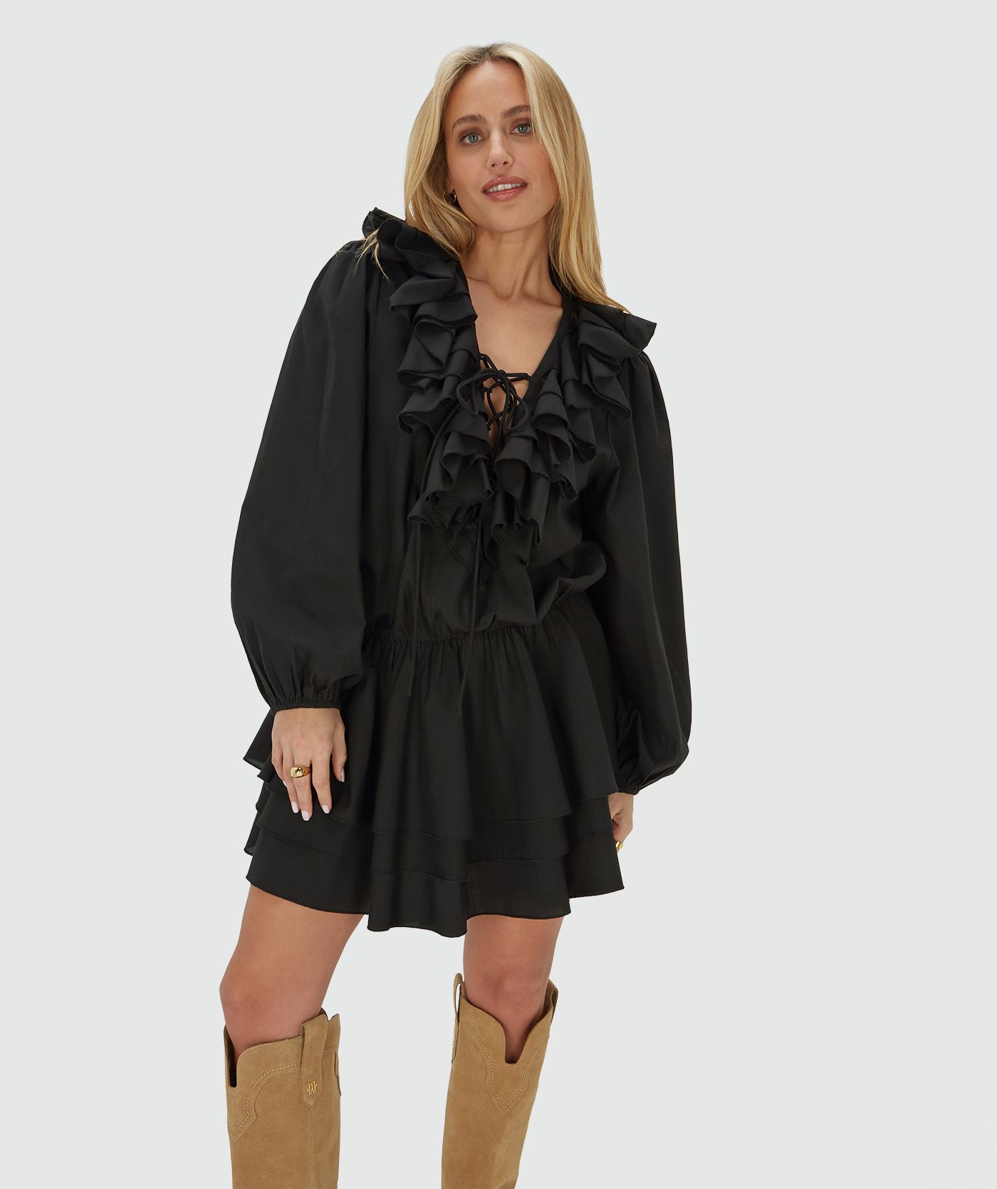 Model draagt een loose fit jurk in zwart, met een ruffle-effect bij de halslijn en in de rok