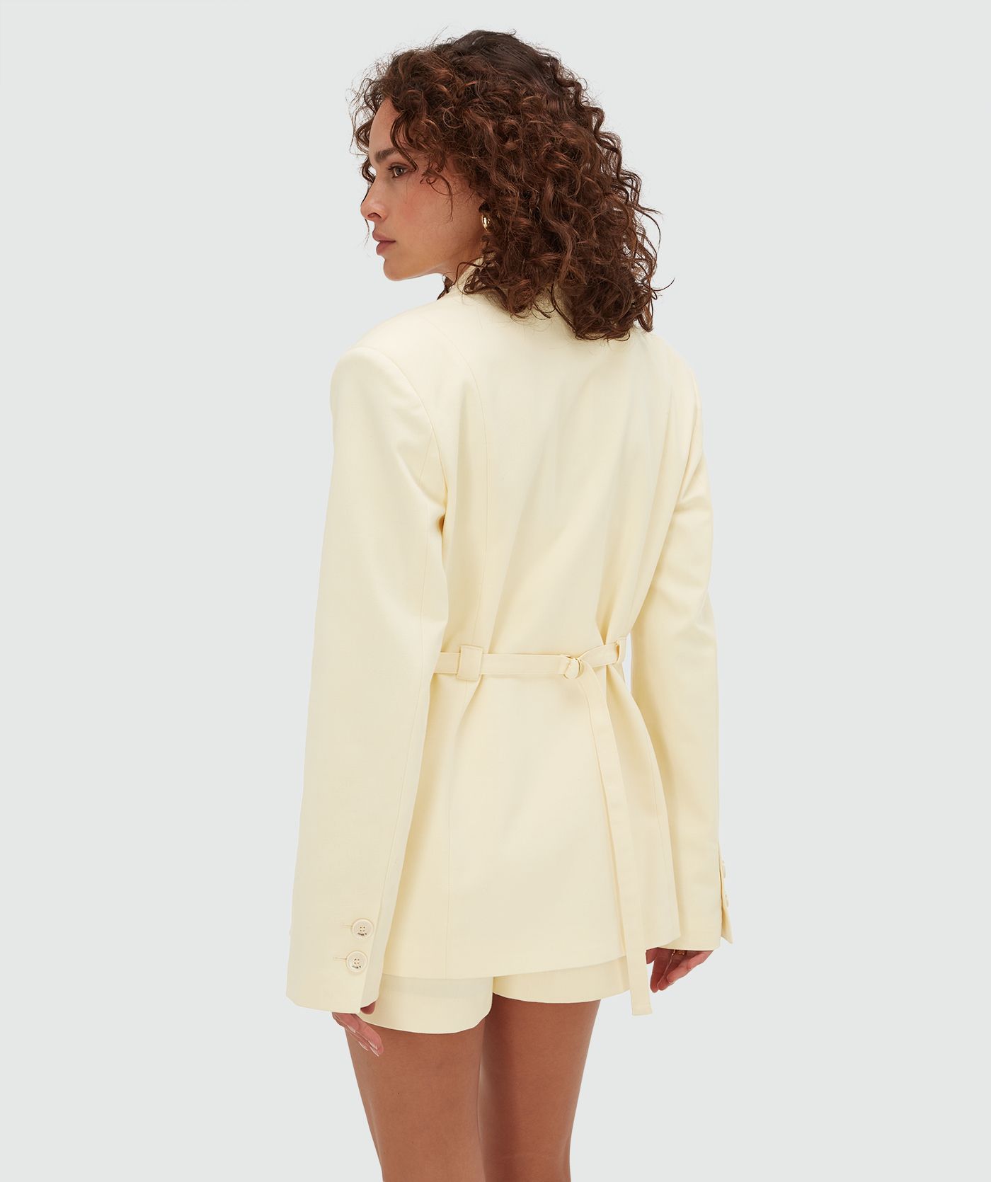 Achterzijde van een model in een oversized blazer in de kleur Butter Yellow