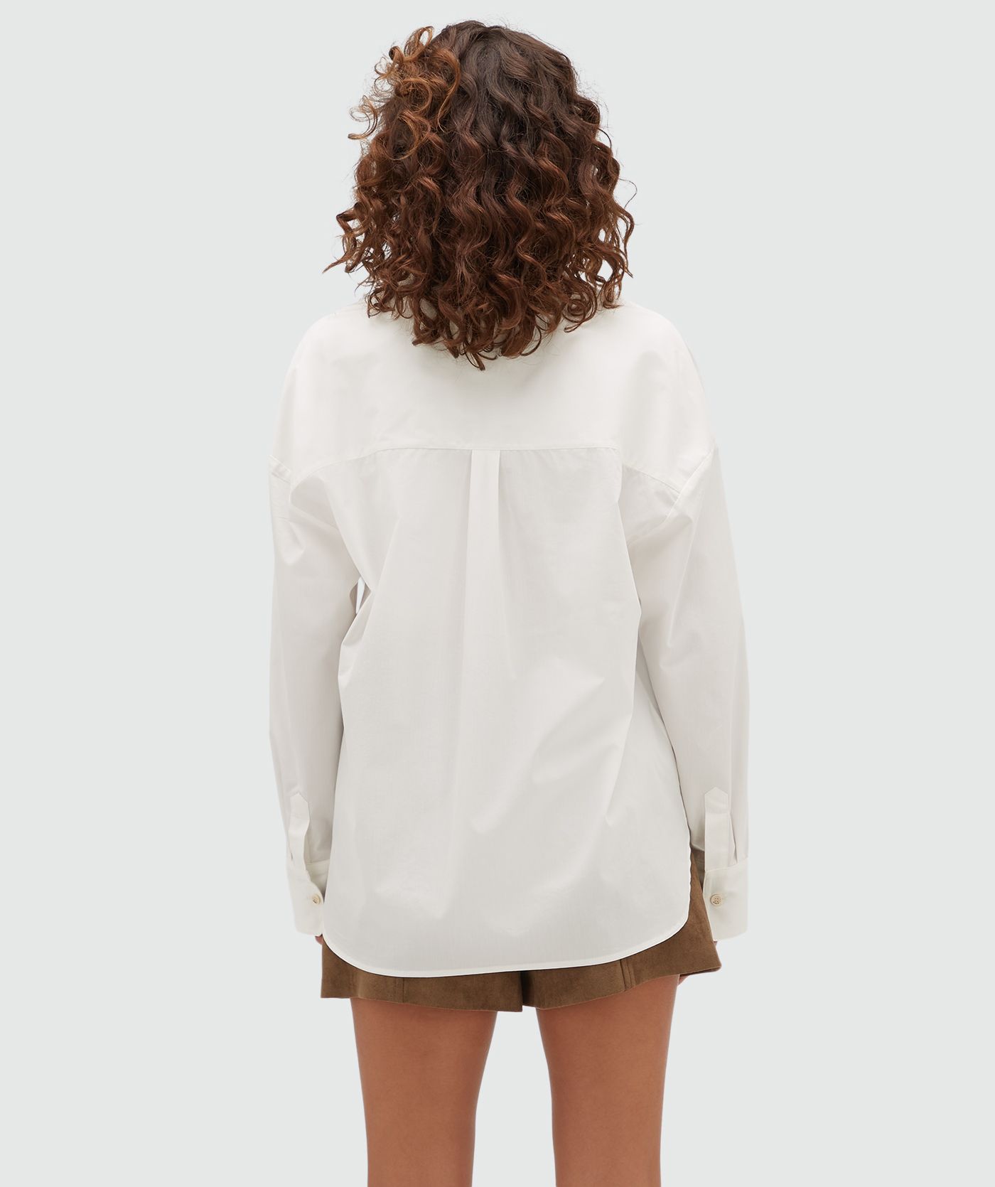 Achteraanzicht van een model in een  oversized witte blouse.
