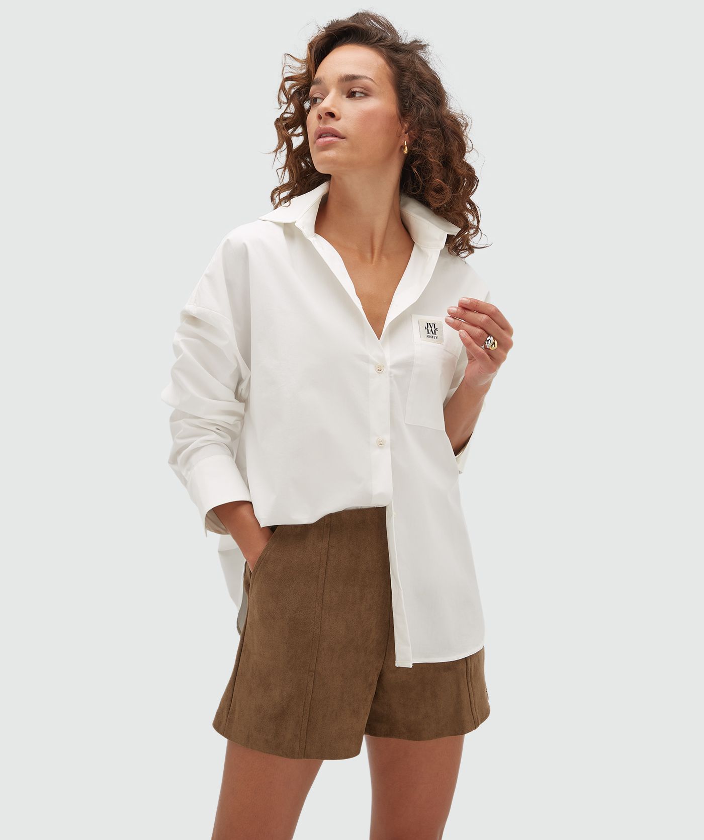 Model draagt een oversized blouse in de kleur wit met een borstzak voorzien van het JOSH V-logo.