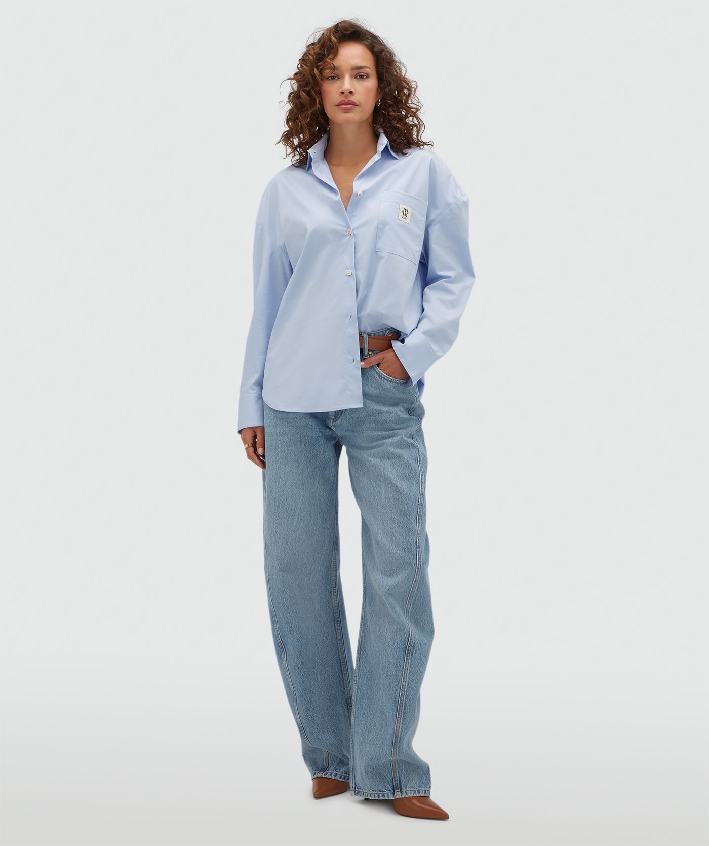 Model draagt een lichtblauwe oversized blouse met een borstzak voorzien van het JOSH V-logo.