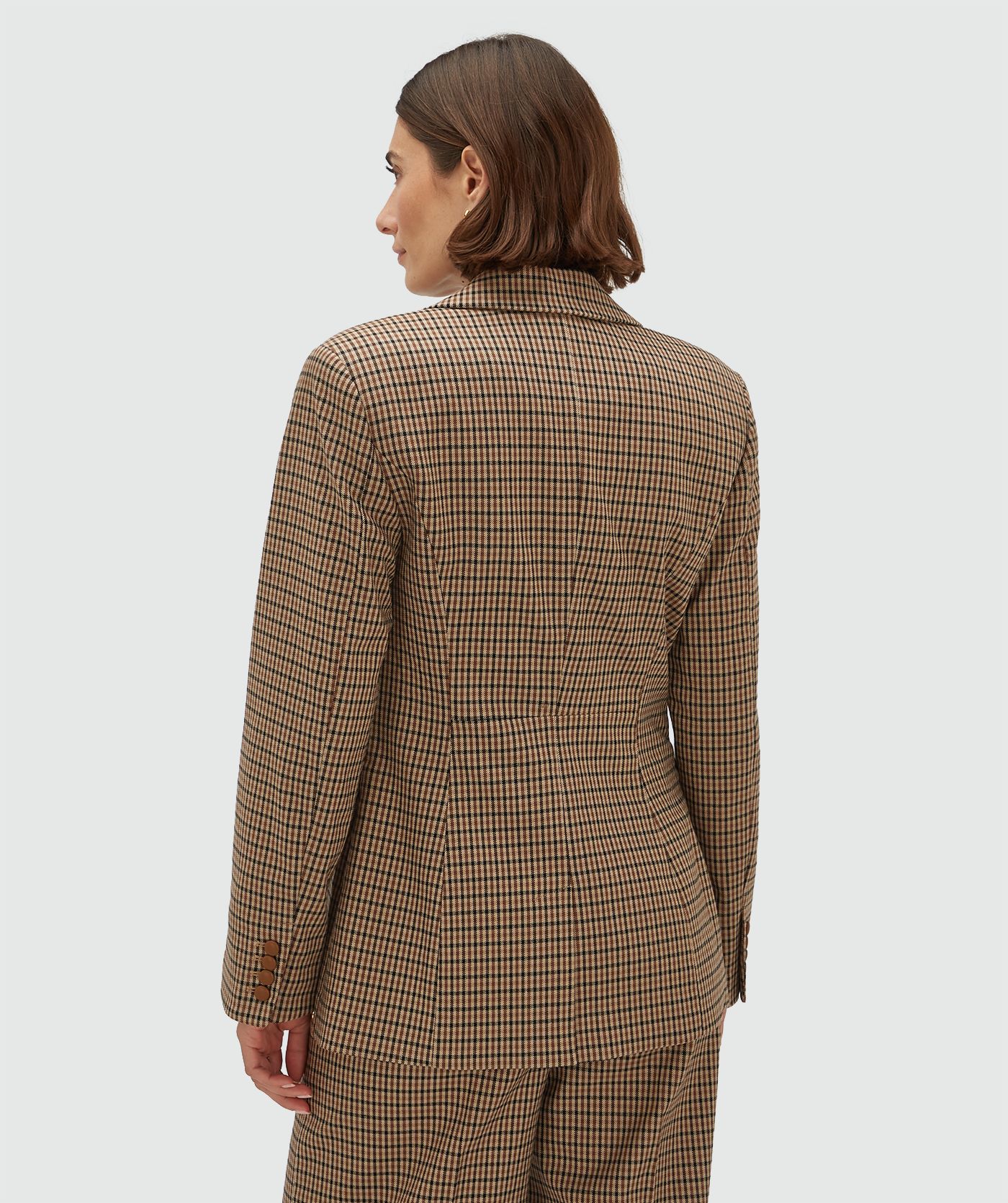 Achteraanzicht van een model in een getailleerde blazer met ruitjes