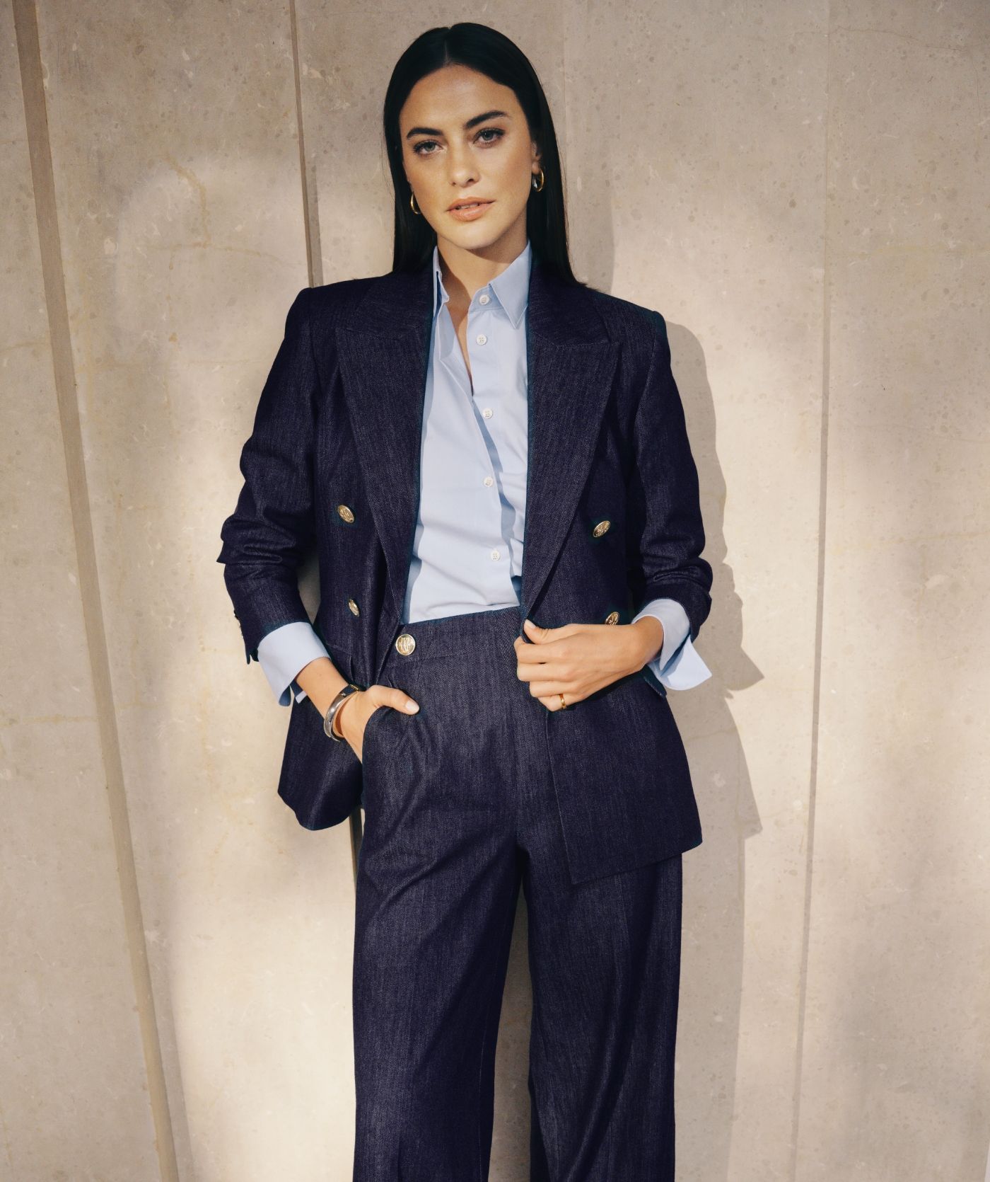Model draagt een donkerblauwe blazer met gouden knopen aan de voorkant.