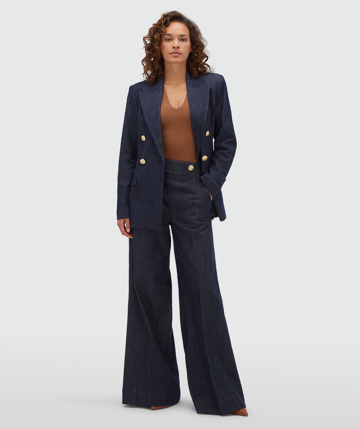 Model draagt een donkerblauwe blazer met gouden knopen aan de voorkant.