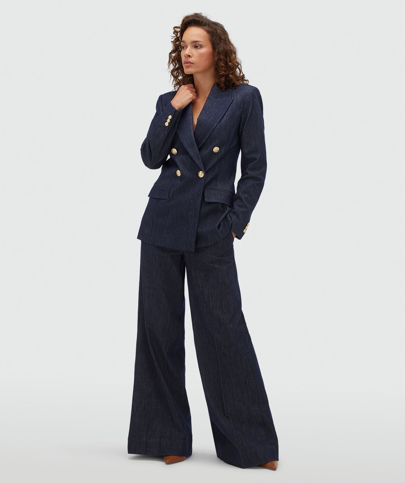 Model draagt een donkerblauwe blazer met gouden knopen aan de voorkant.