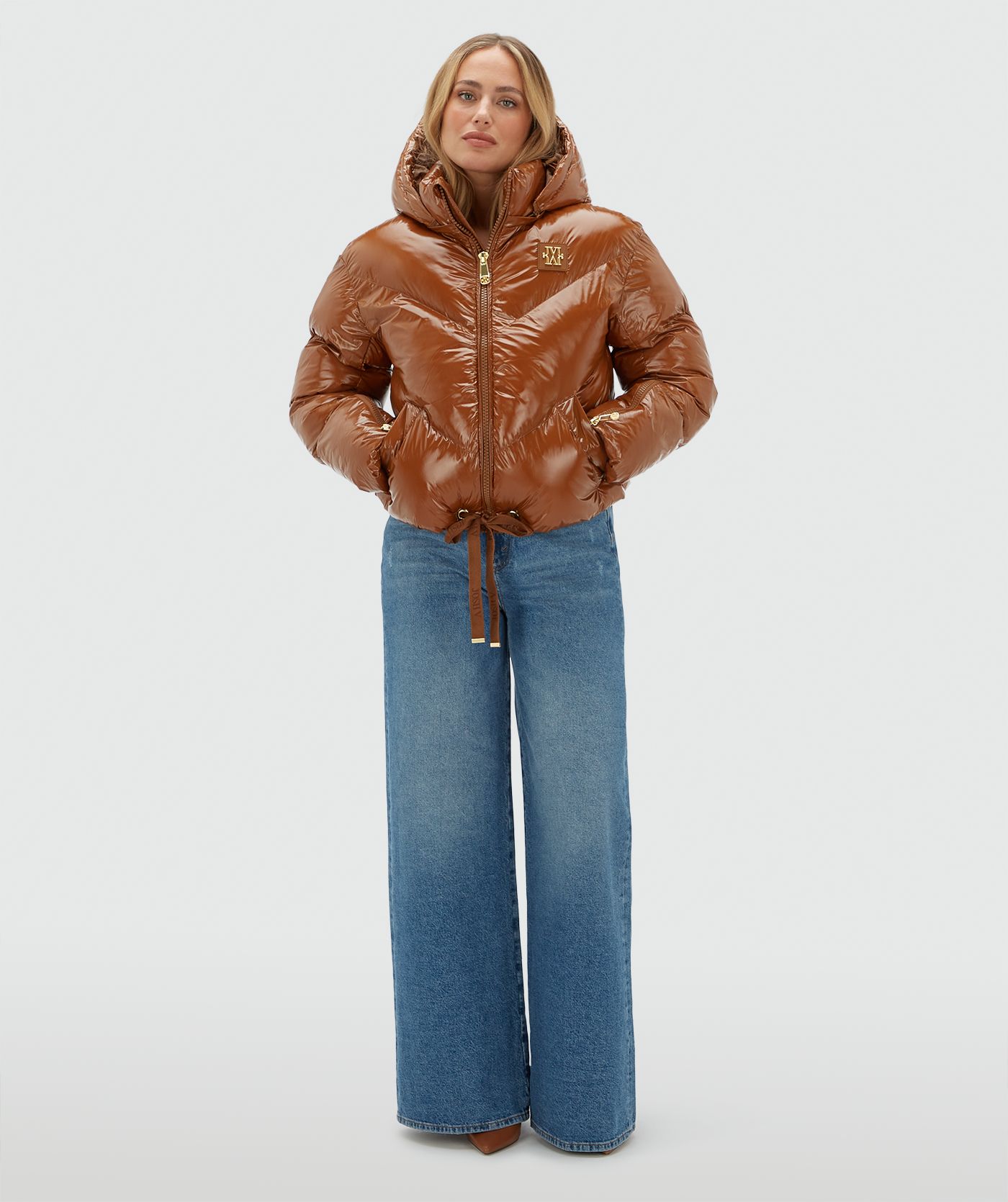 Model draagt een cognac kleurige lak look jas gecombineerd met een jeans.