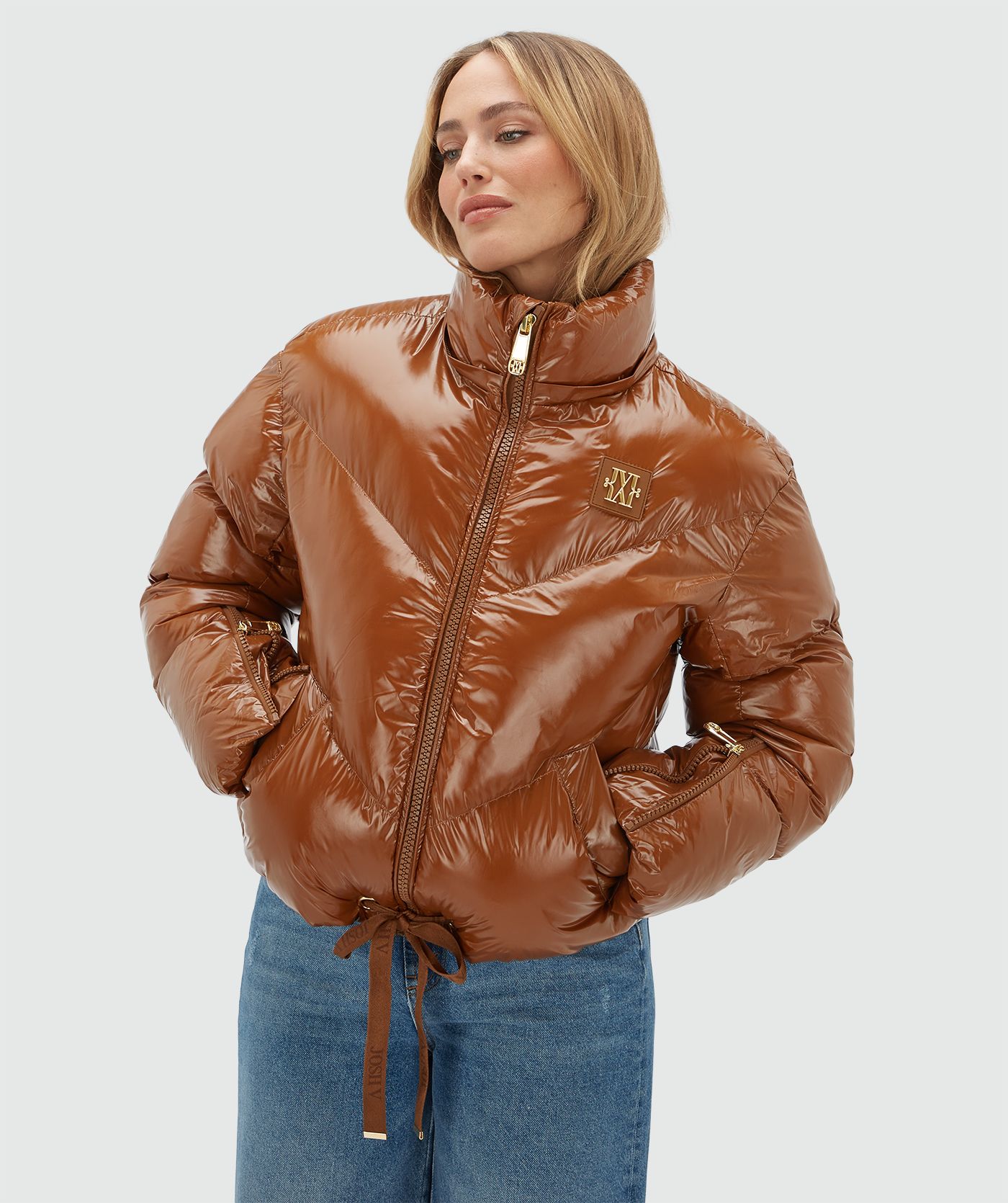 Model draagt een cognac kleurige lak look jas gecombineerd met een jeans.