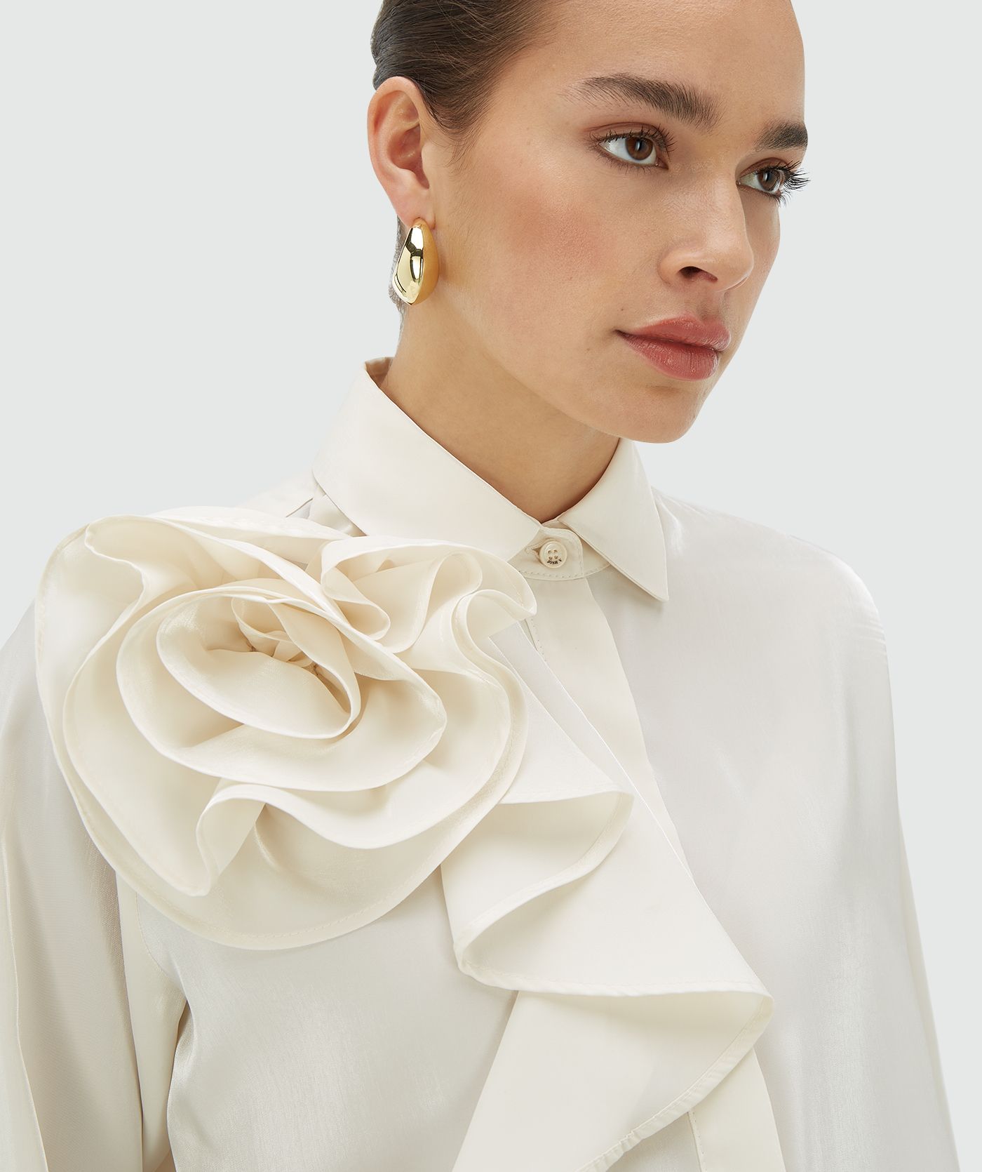 Model draagt een creme white blouse met bloem op de schouder aan de voorzijde - JOSH V