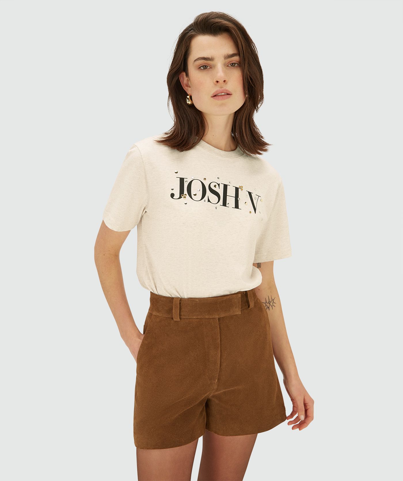Model draagt een Ecru Melange oversized short sleeve T-shirt met ronde hals. Het T-shirt heeft een JOSH V logo op de borst met strass-steentjes