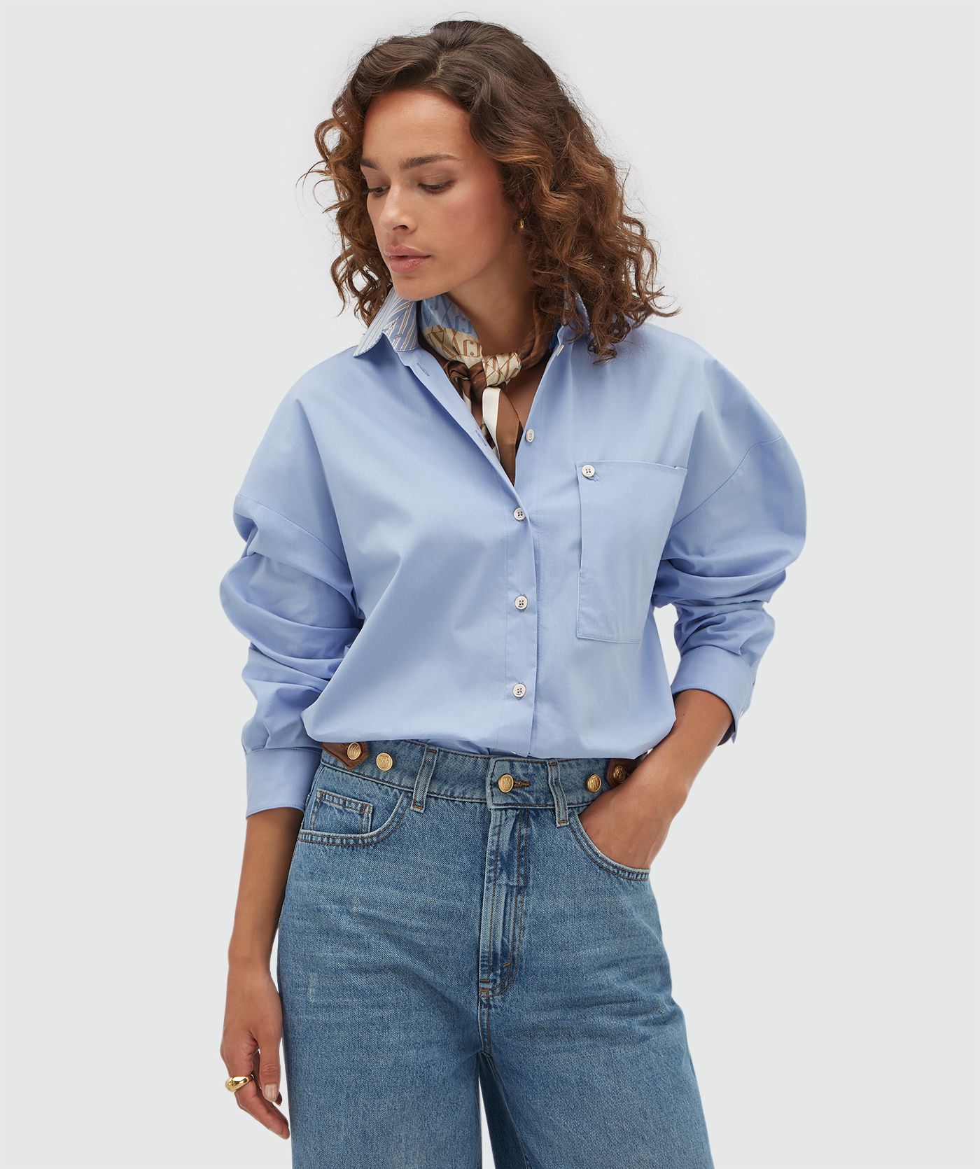 Model draagt een lichtblauwe blouse met het sjaaltje.