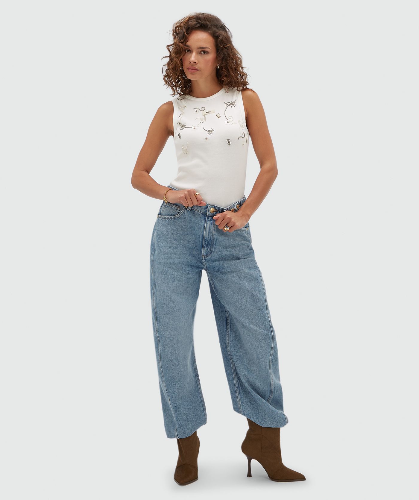 Model draagt een wit topje met aan de voorkant kralen details.
