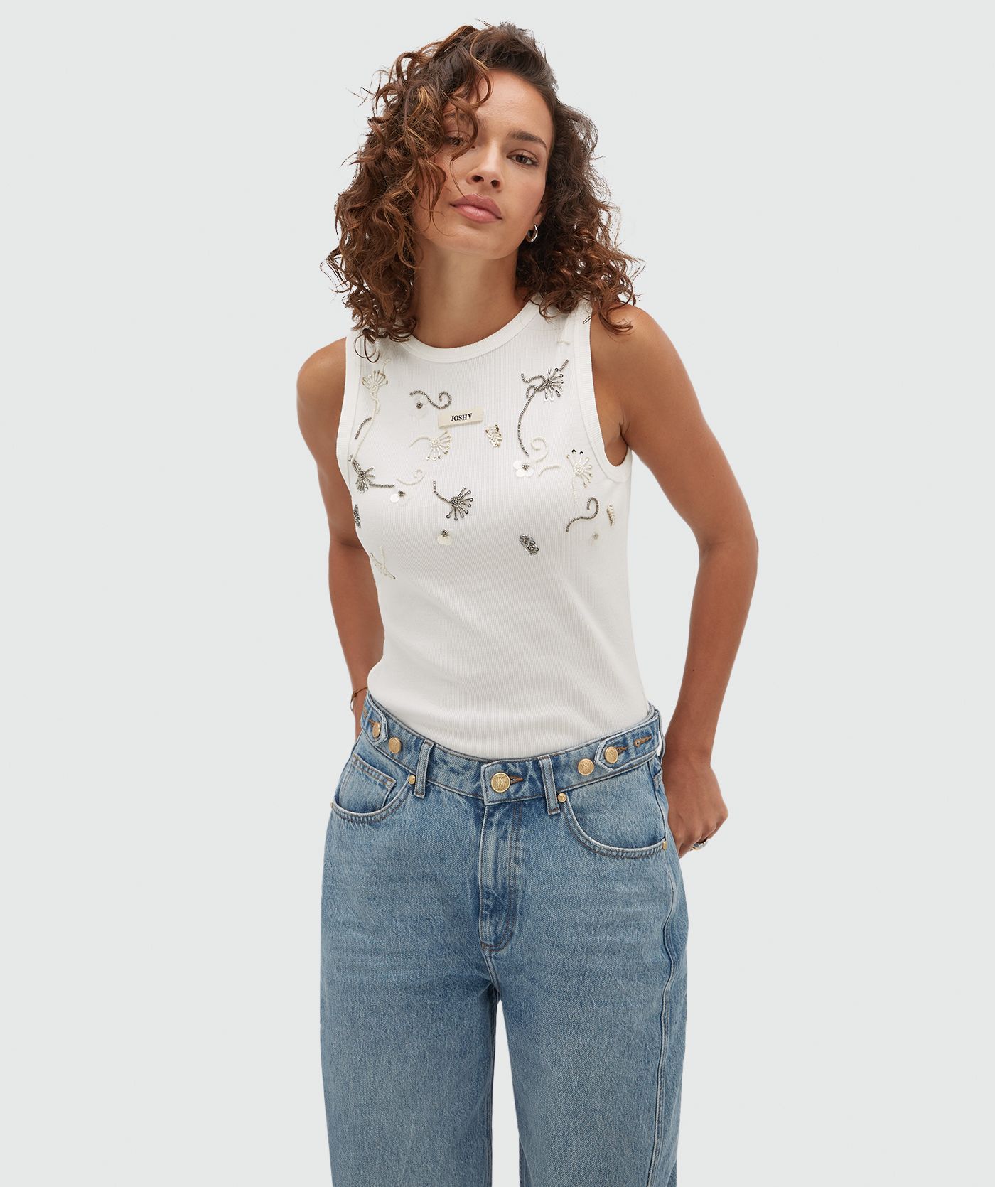 Model draagt een wit topje met aan de voorkant kralen details.