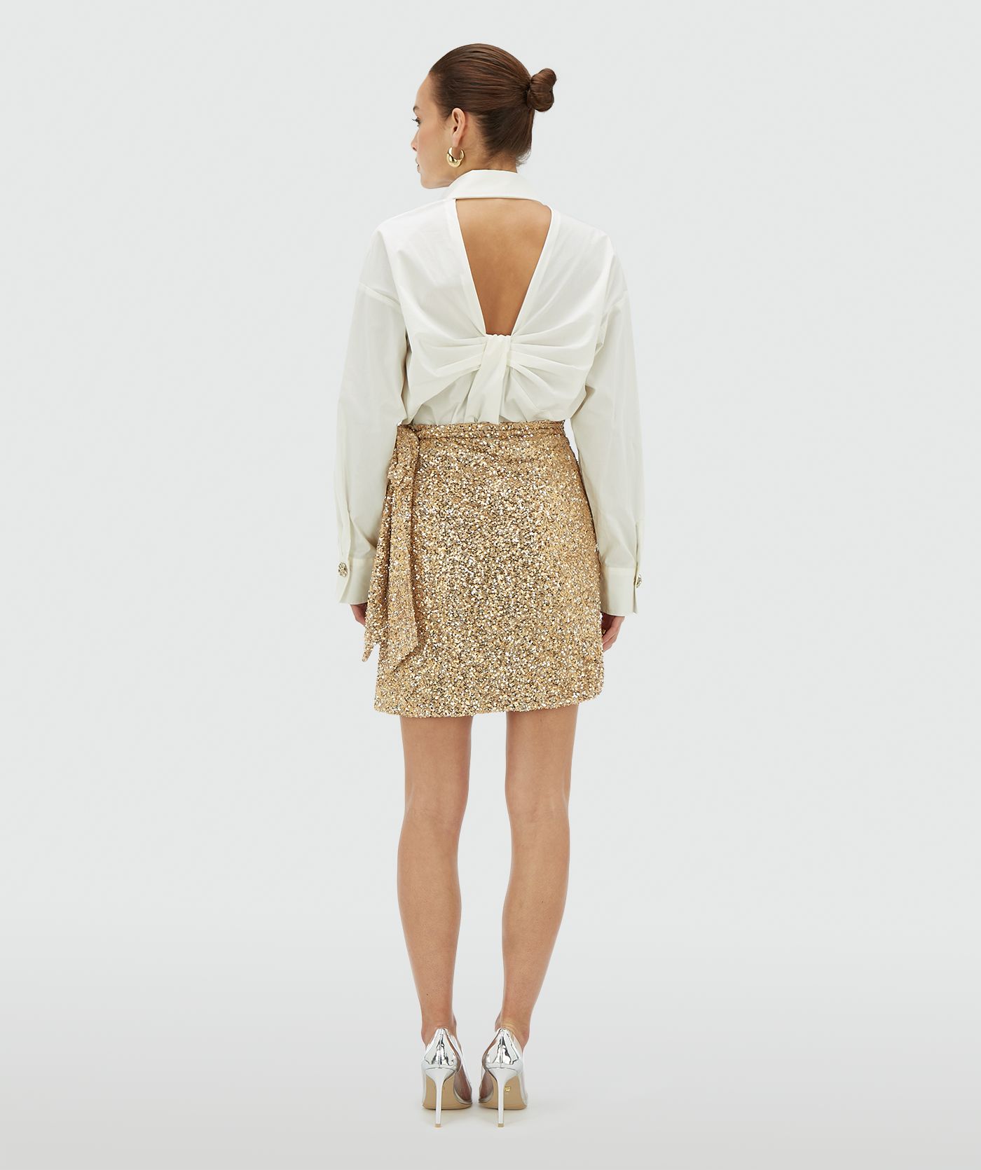 Achteraanzicht van een model in een goud zilver pailletten rok met striksluiting - JOSH V