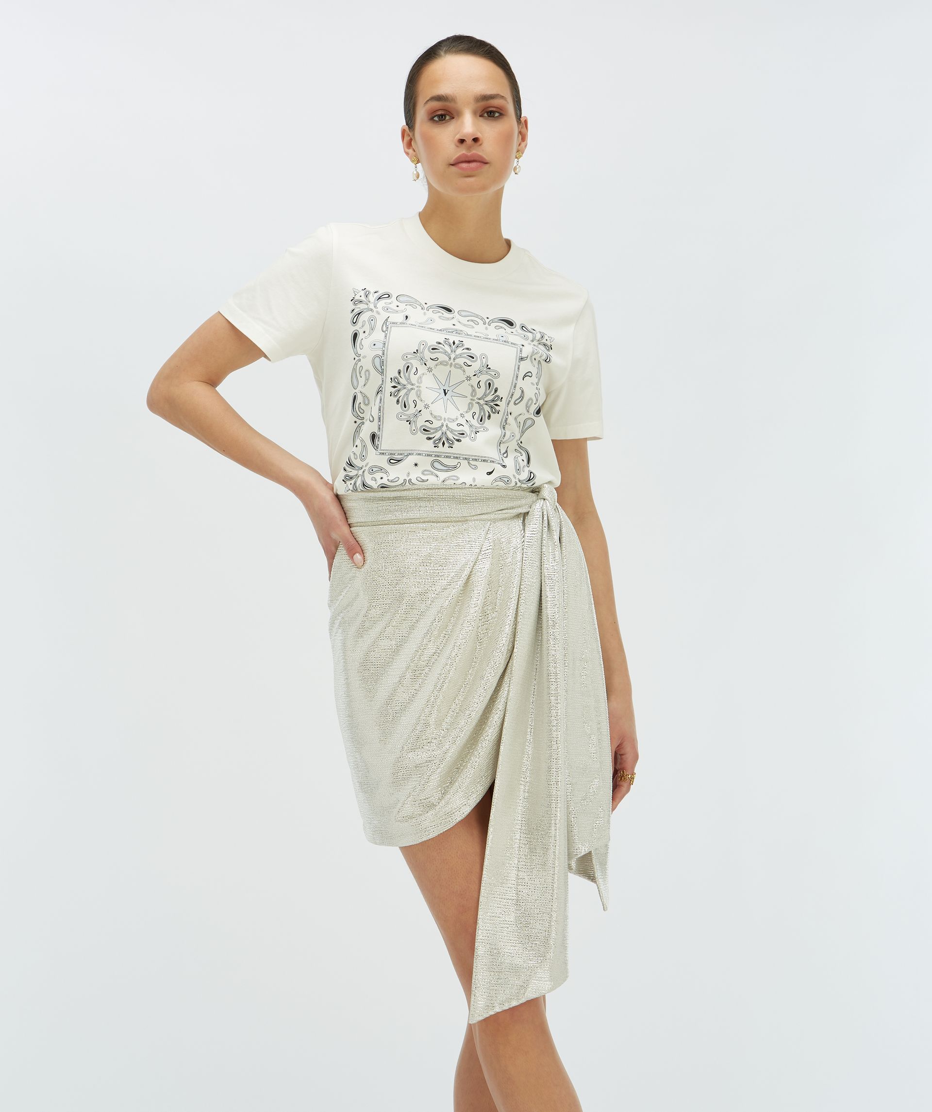 Model draagt metallic zilverkleurige overslagrok gecombineerd met het Dorie Bandana T-shirt - Josh V.