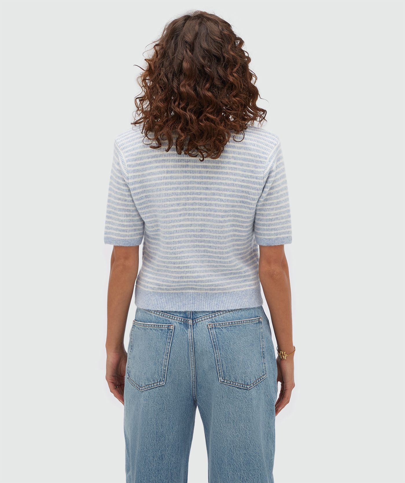 Achteraanzicht van een model in een lichtblauw wit gestreept vestje.