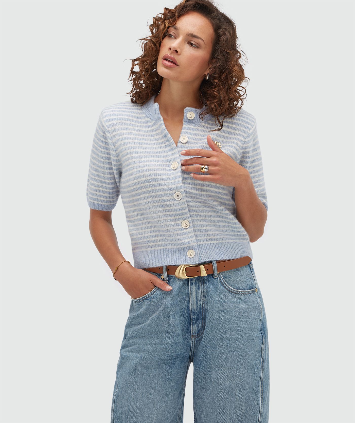 Model draagt een lichtblauw wit gestreept vestje met korte mouwen.