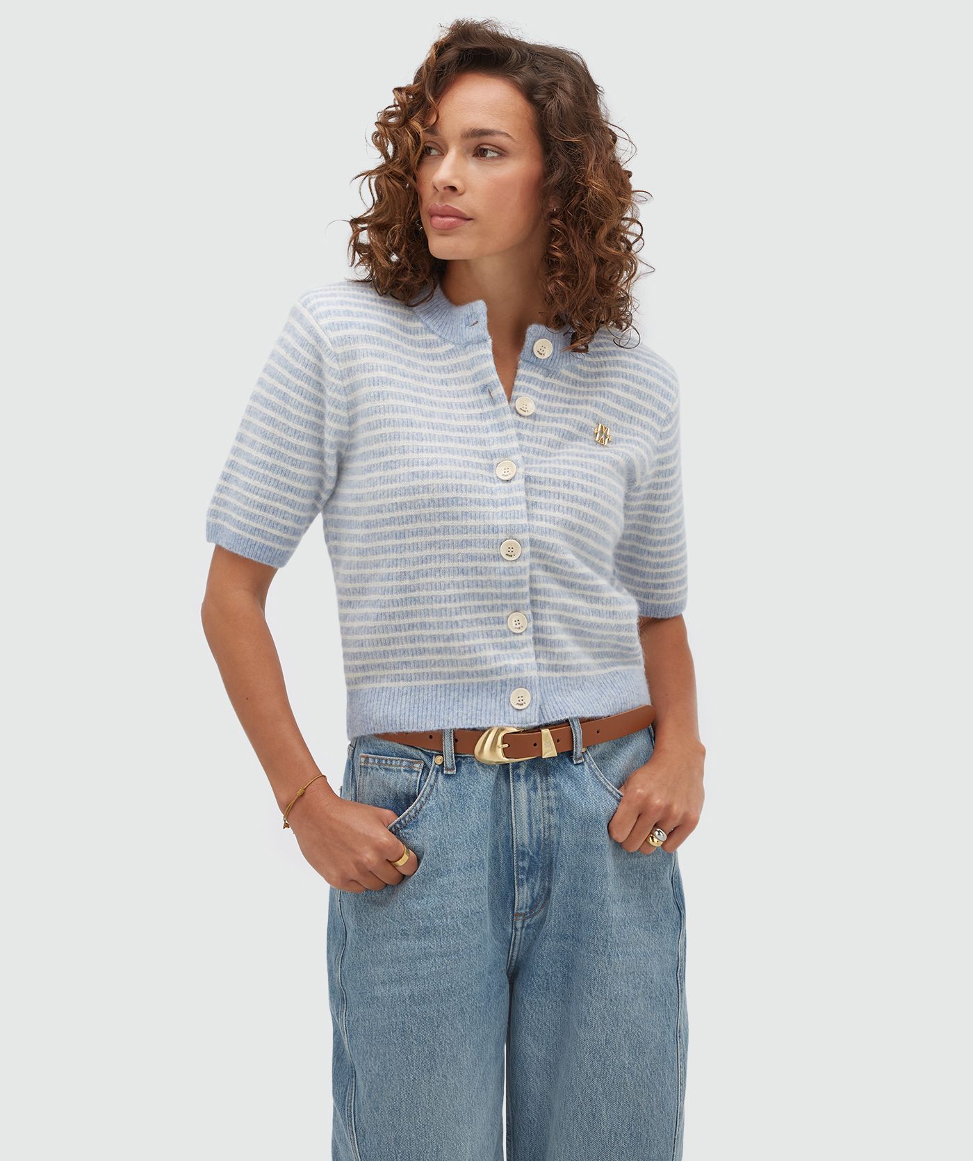 Model draagt een lichtblauw wit gestreept vestje met korte mouwen.