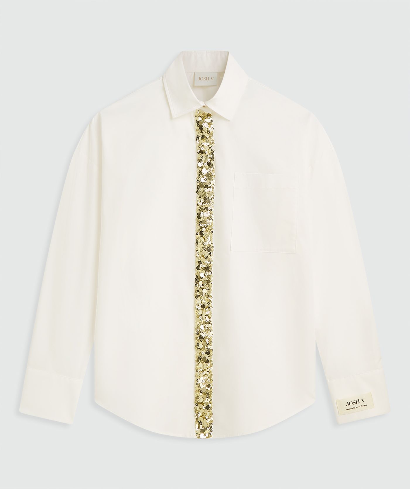 Off witte blouse met een verticale strook goudkleurige strass-steentjes aan de voorzijde zonder model, weergegeven op een lichtgrijze achtergrond