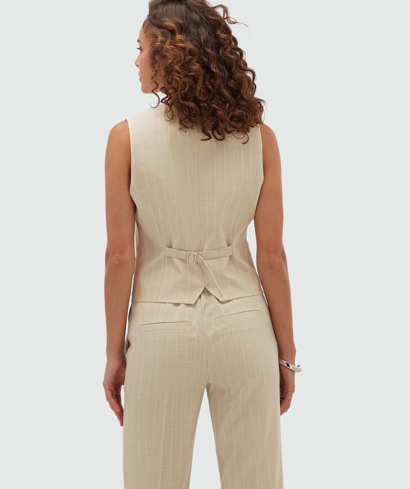 Achteraanzicht van een model in een fitted gilet met krijtstreep en de bijpassende Kora pantalon. 
