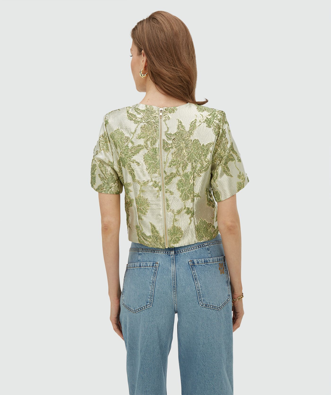 Achteraanzicht van een model in een cropped top met metallic details in de kleur Dark Pistachio