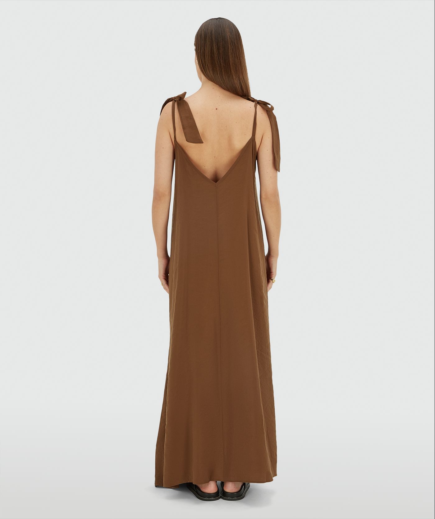 Achteraanzicht van een model in een maxi jurk met striksluiting in de kleur Brown