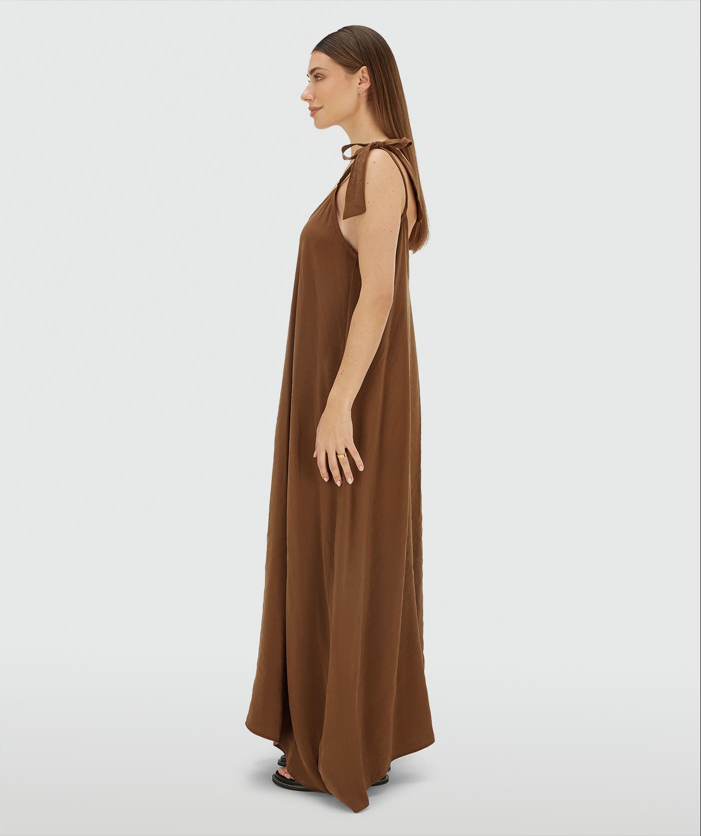Zijaanzicht van een model in een maxi jurk met striksluiting in de kleur Brown