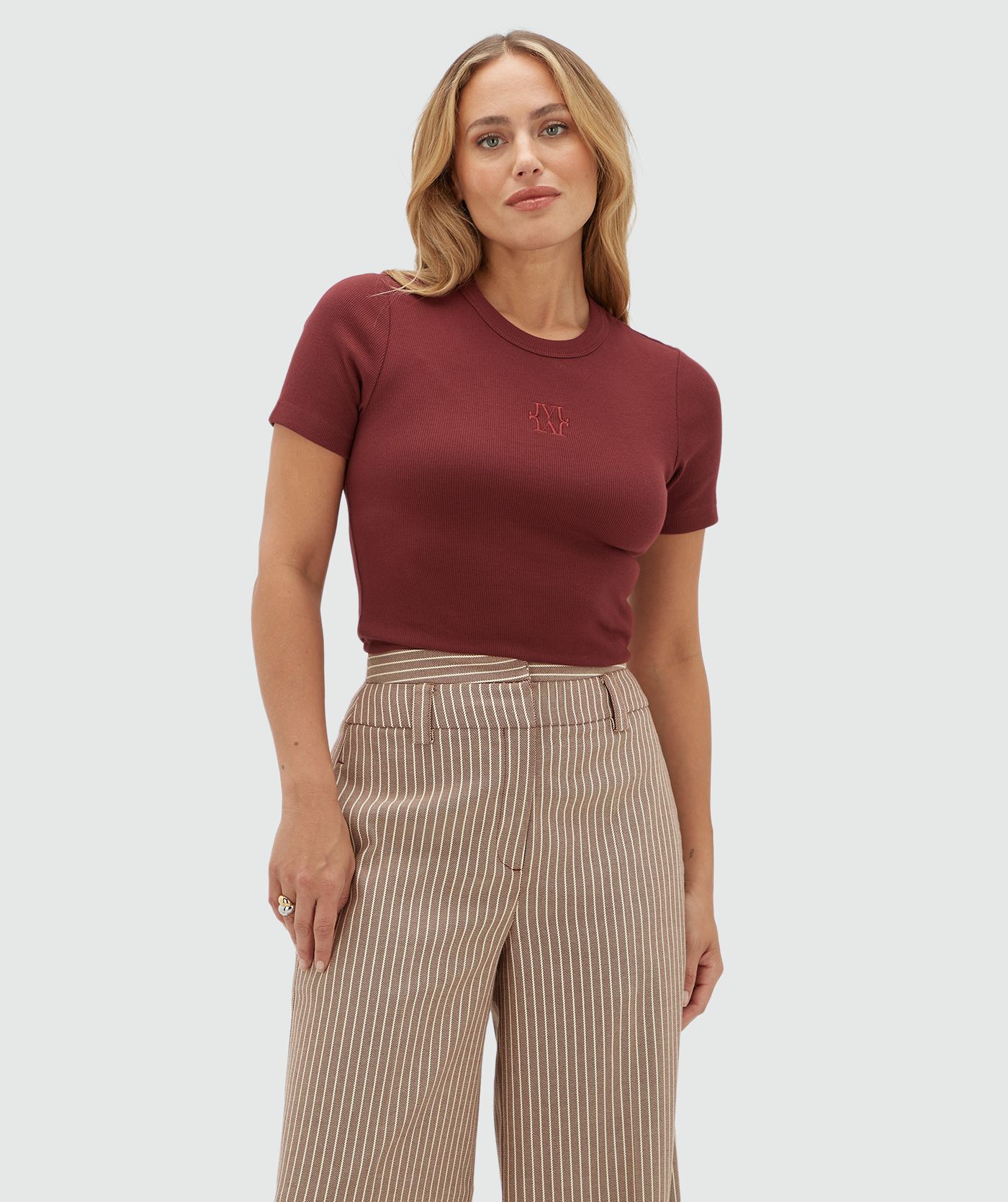 Model draagt donkerrood T-shirt met een JOSH V logo op de borst gecombineerd met een donkerrood wit gestreepte pantalon.