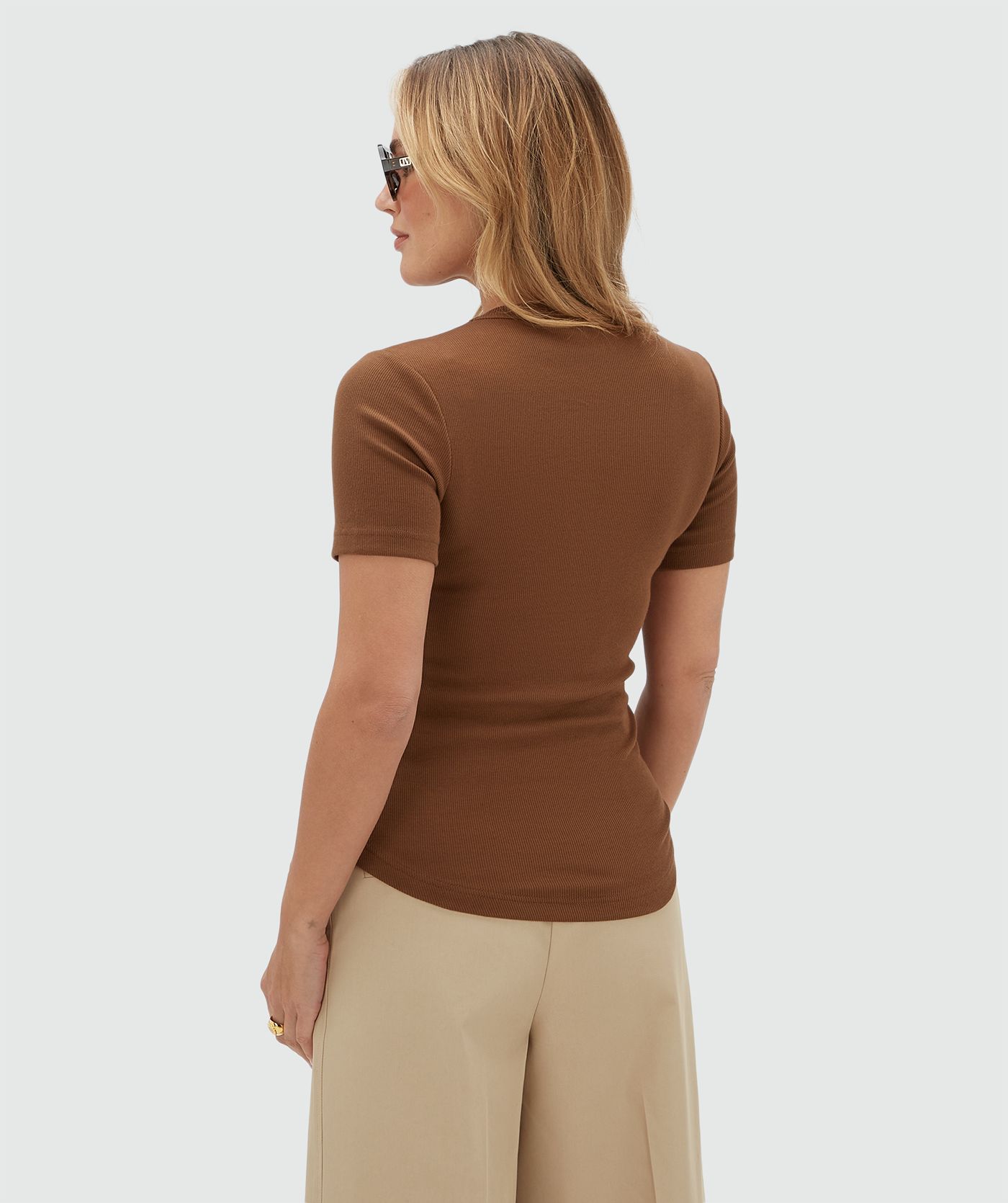 Achteraanzicht van een model in een donkerbruin T-shirt.