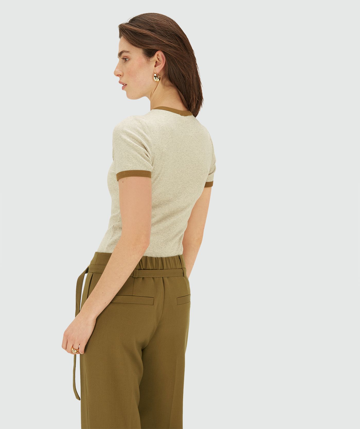 Model draagt een Ecru Melange ribgebreid T-shirt met contrasterende boord bij de hals en mouwen en een subtiel JOSH V-label op de borst