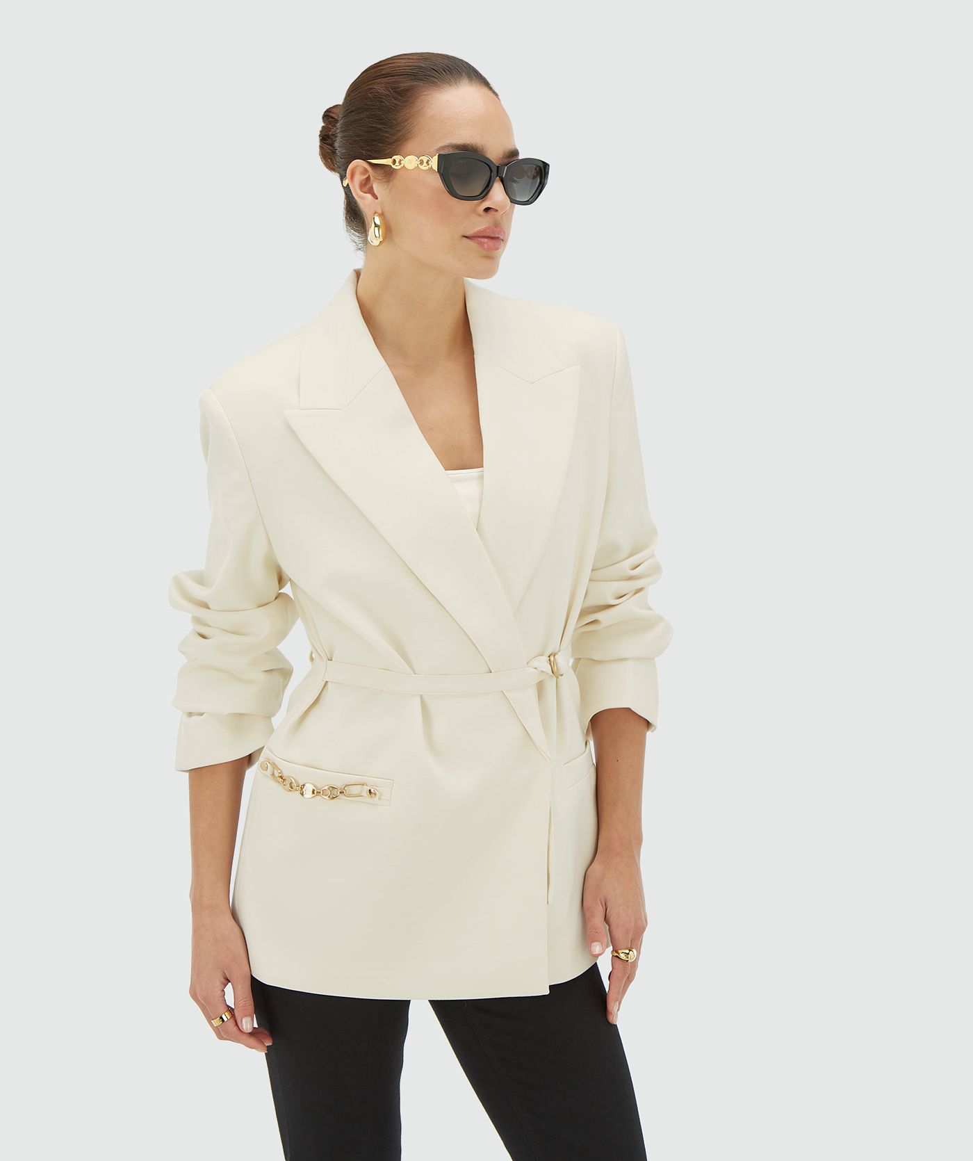 Model draagt Creme White oversized blazer met schoudervullingen. De blazer heeft een JOSH V branded chain op de steekzak en riem met branded haakjes - JOSH V
