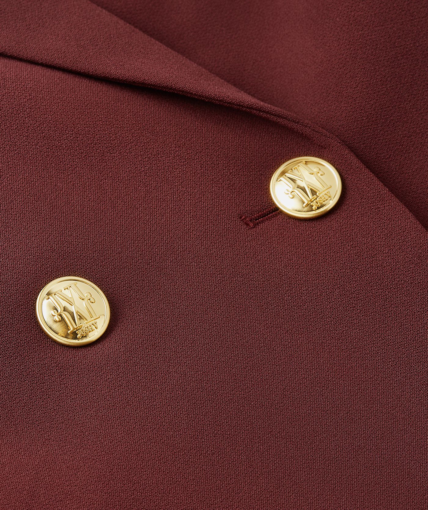 Close-up van de gouden knopen aan de voorkant van de donkerrode blazer.