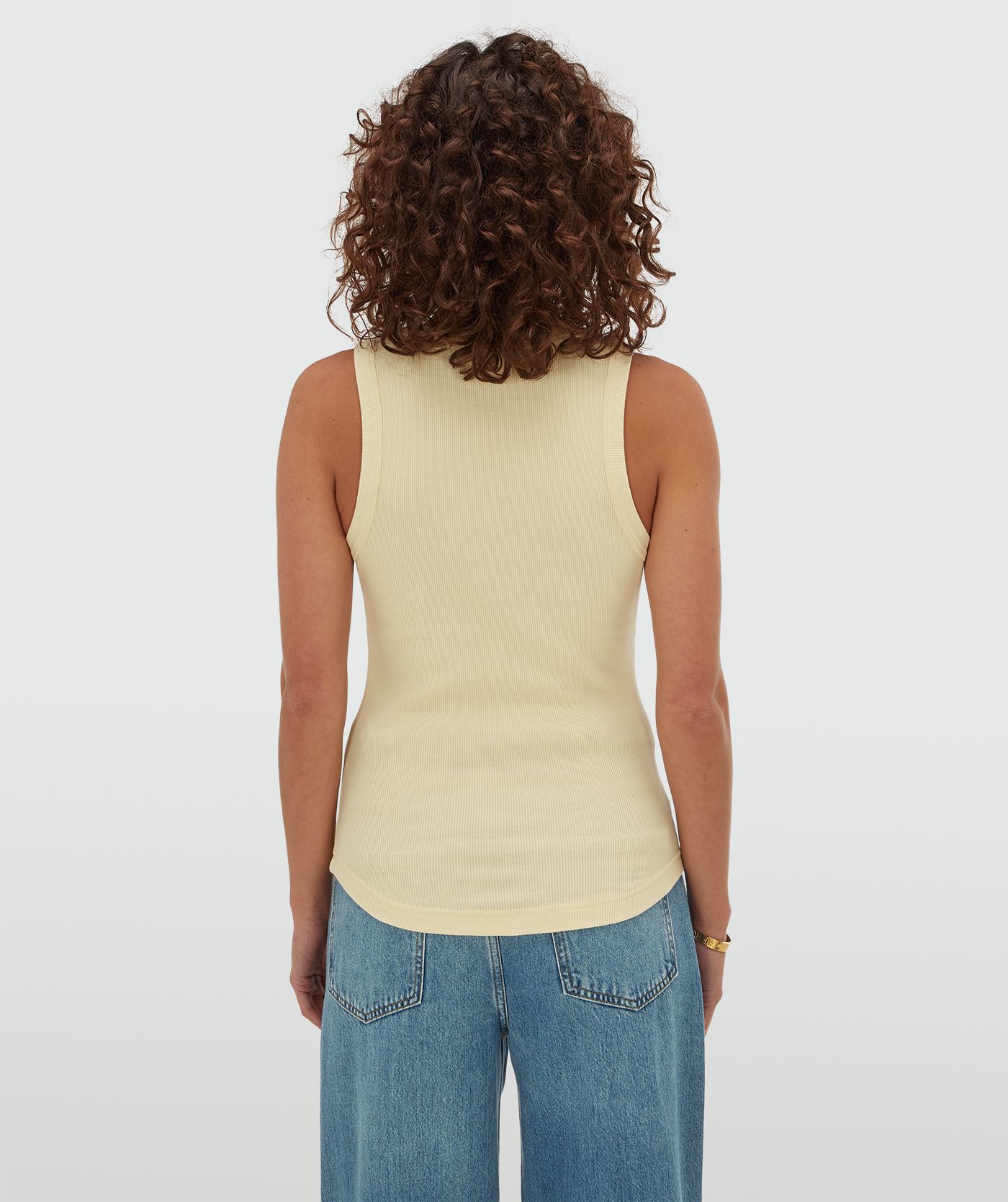 Achterzijde van een model in een slim fit top met logo in de kleur Butter Yellow