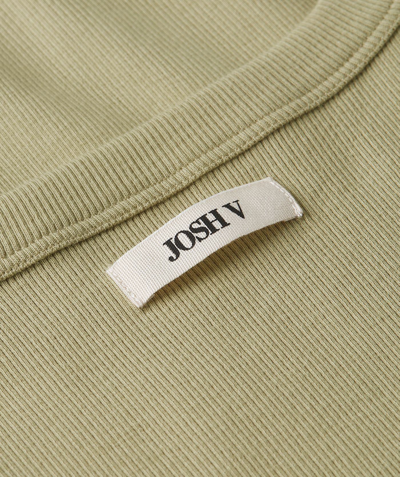 Close-up van een slim fit top met logo in de kleur Dark Pistachio