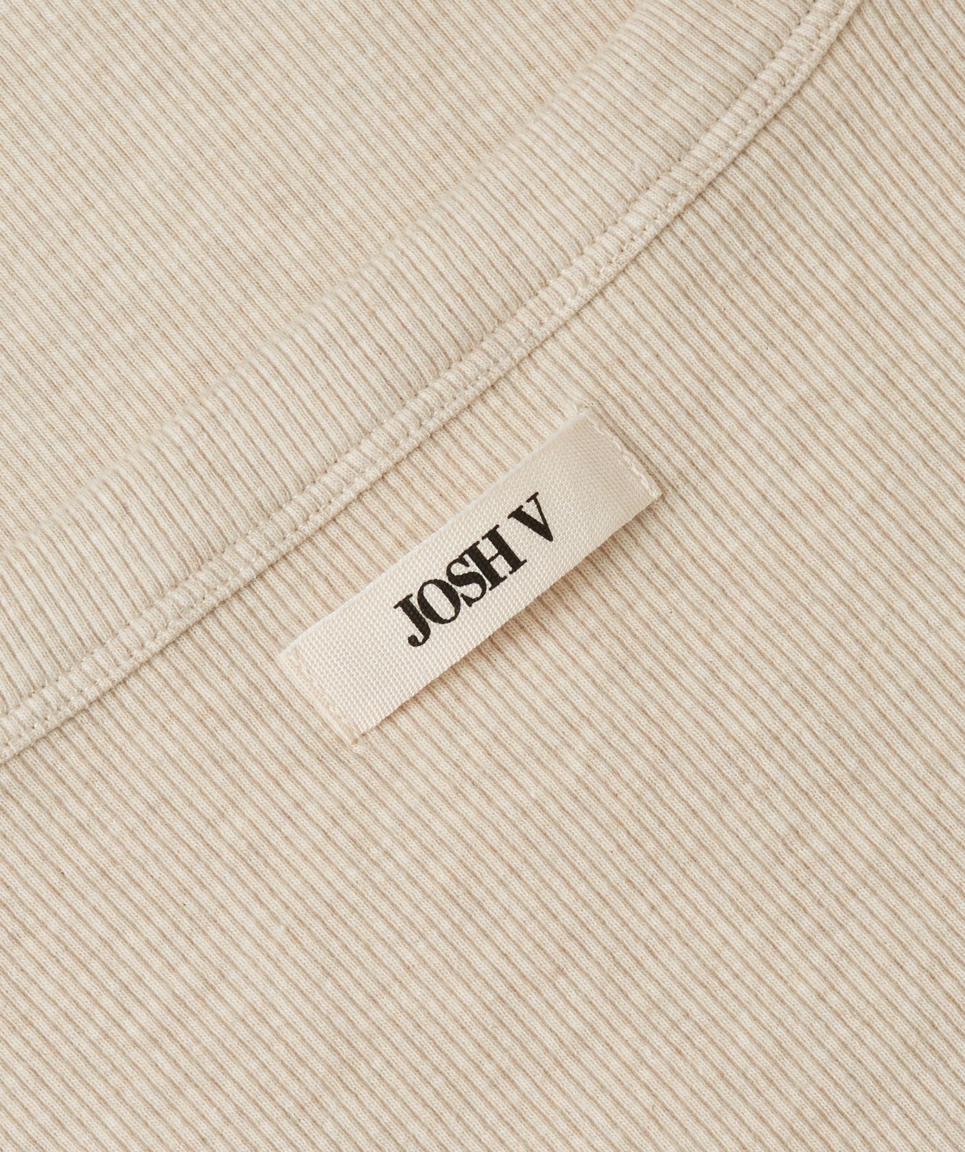 Close-up van een slim fitted top met logo, in de kleur Oat Melange