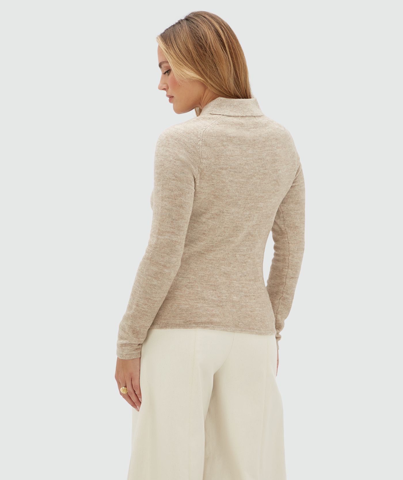 Achteraanzicht van een model in een beige vestje met kraag.