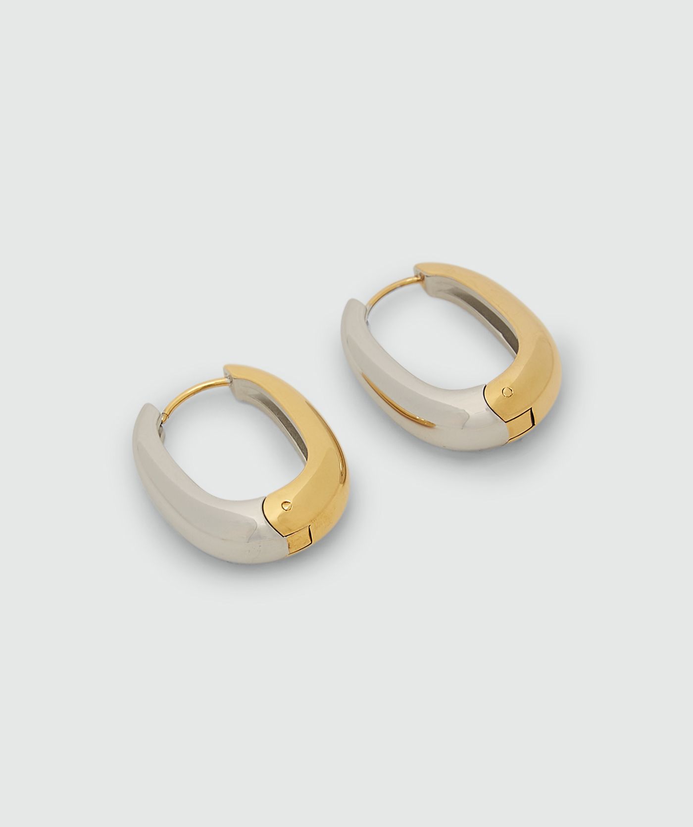 Oorbellen met goud en zilver zonder model, weergegeven op een lichtgrijze achtergrond.