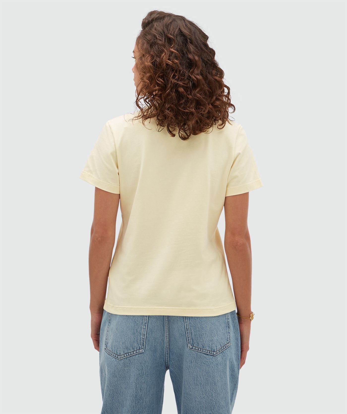 Achteraanzicht van een model in een geel T-shirt.