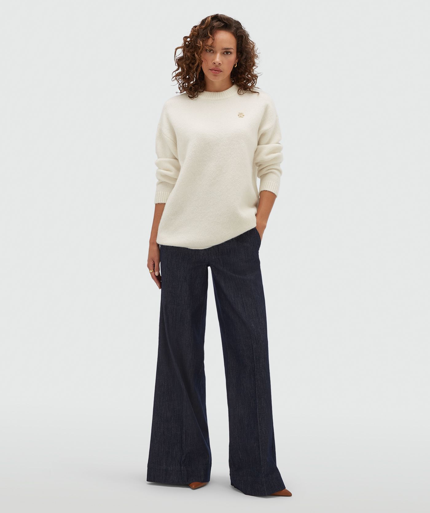 Model draagt een gebroken witte oversized trui met een klein JOSH V-logo op de borst.
