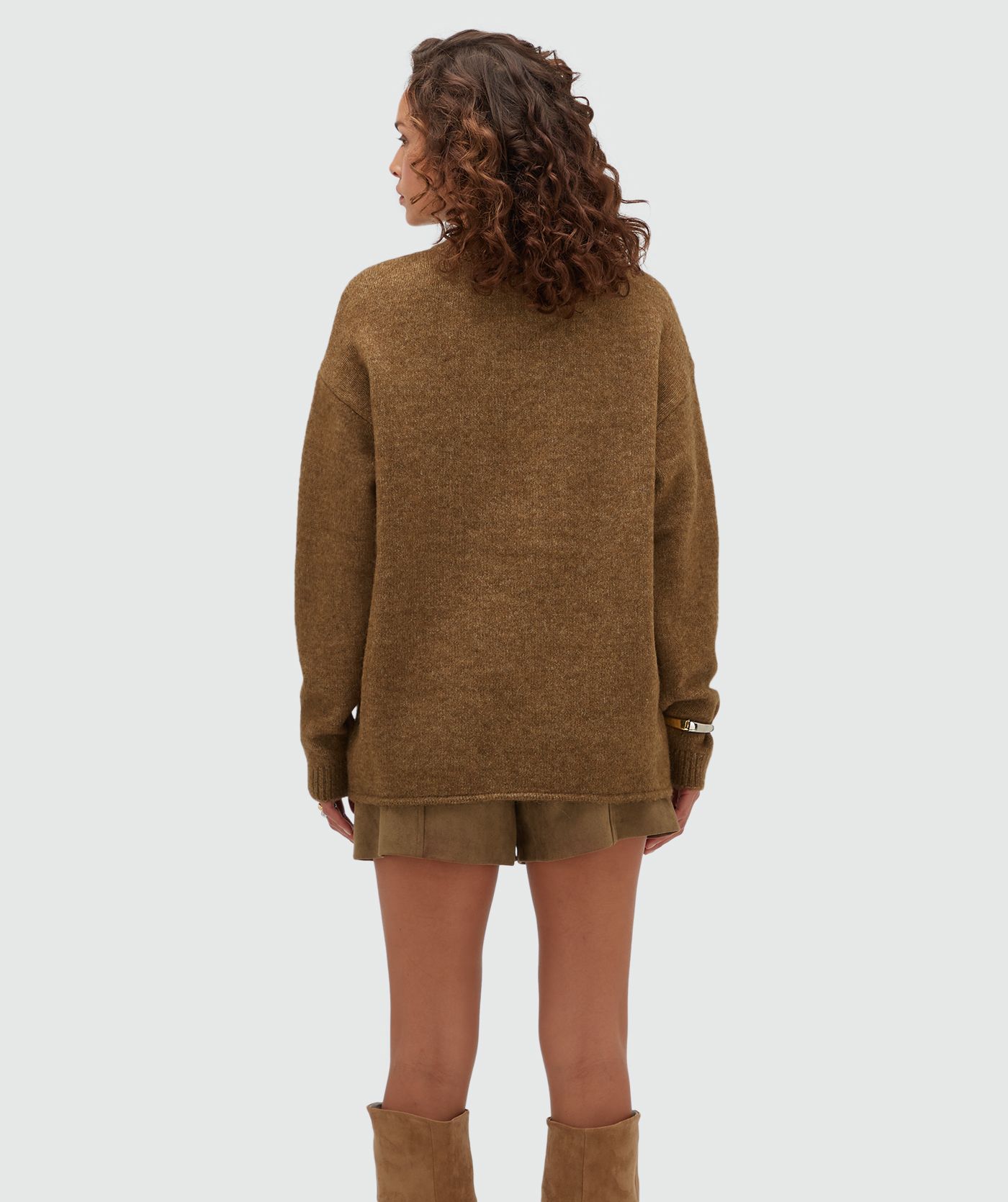 Achteraanzicht van een model in een donkerbruine oversized trui.
