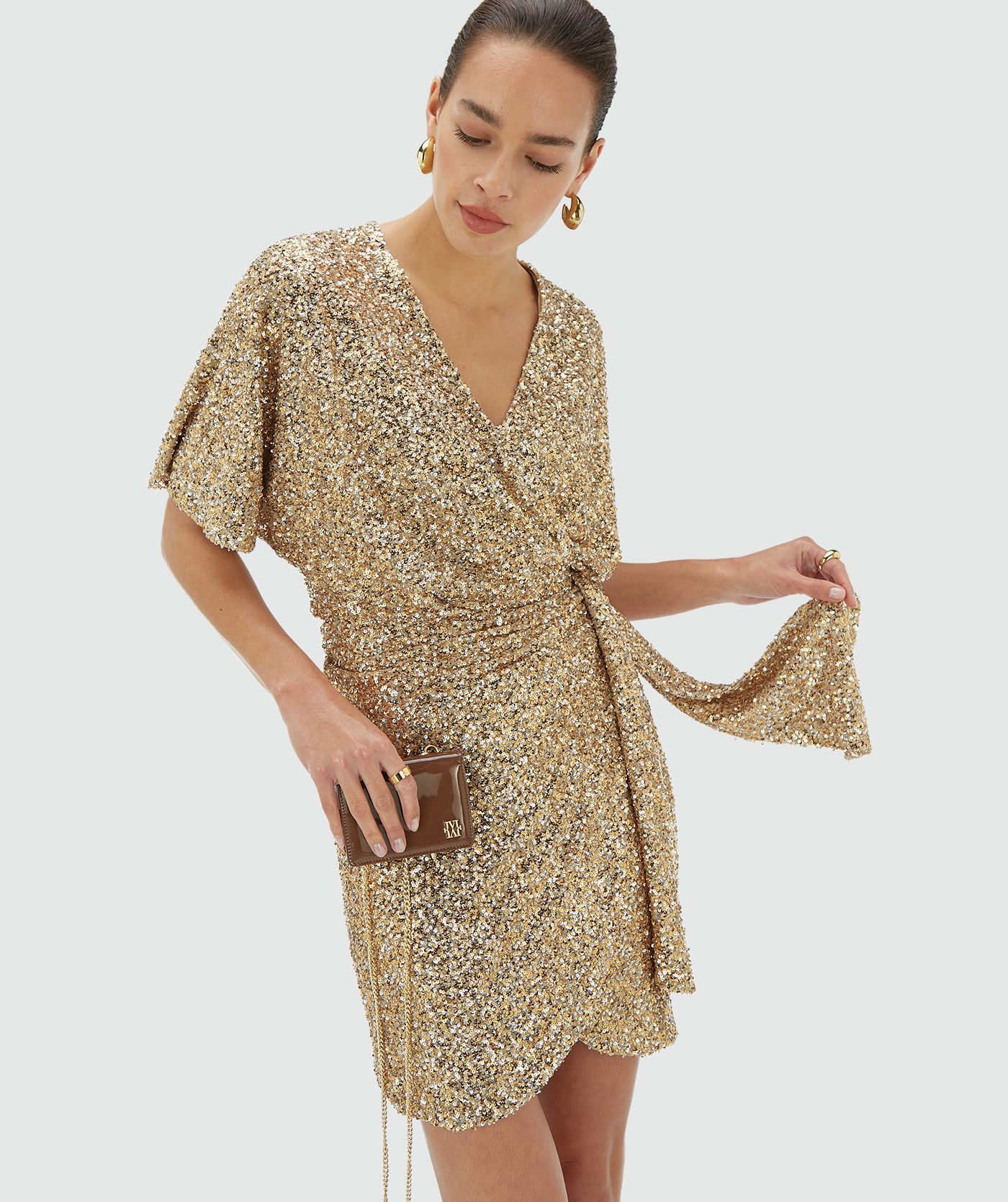 Model draagt een gouden pailletten jurk met strijkdetail aan de voorkant - JOSH V