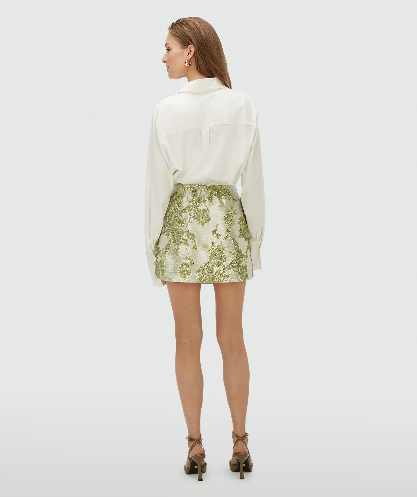 Achteraanzicht van een model in een high waisted rok met metallic details in de kleur Dark Pistachio